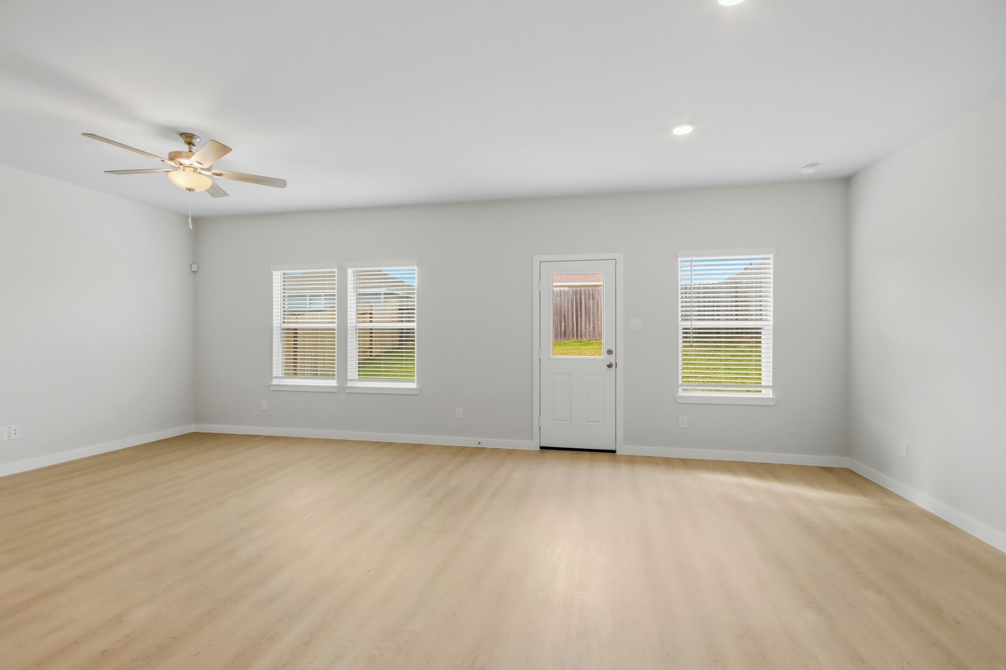 A room with a ceiling fan and a wood floor.