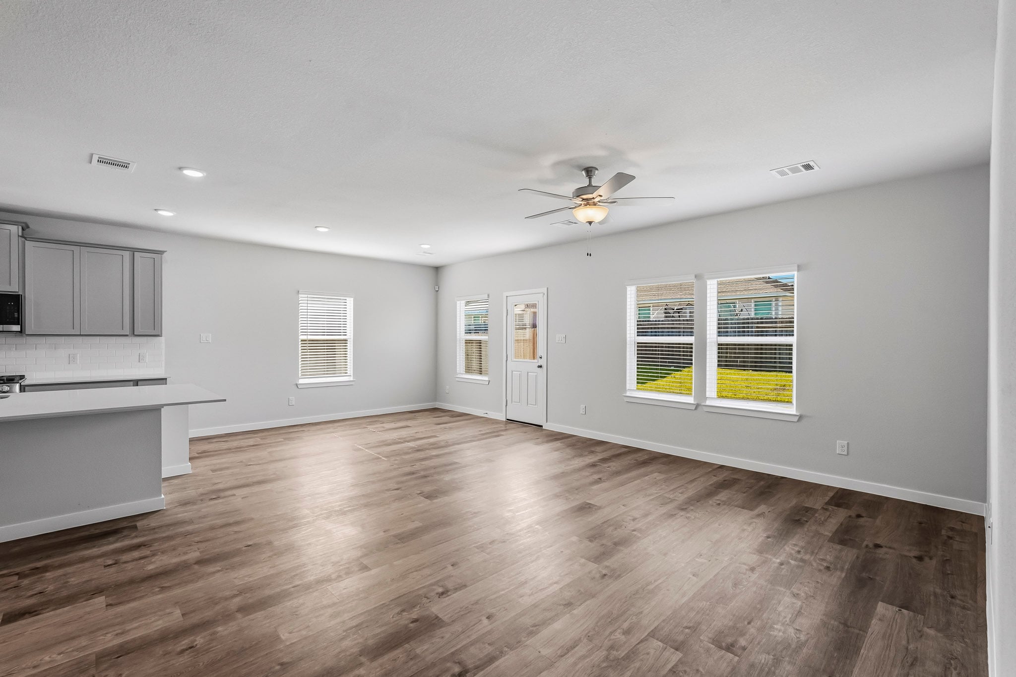 A large empty room with a wood floor and a ceiling fan.