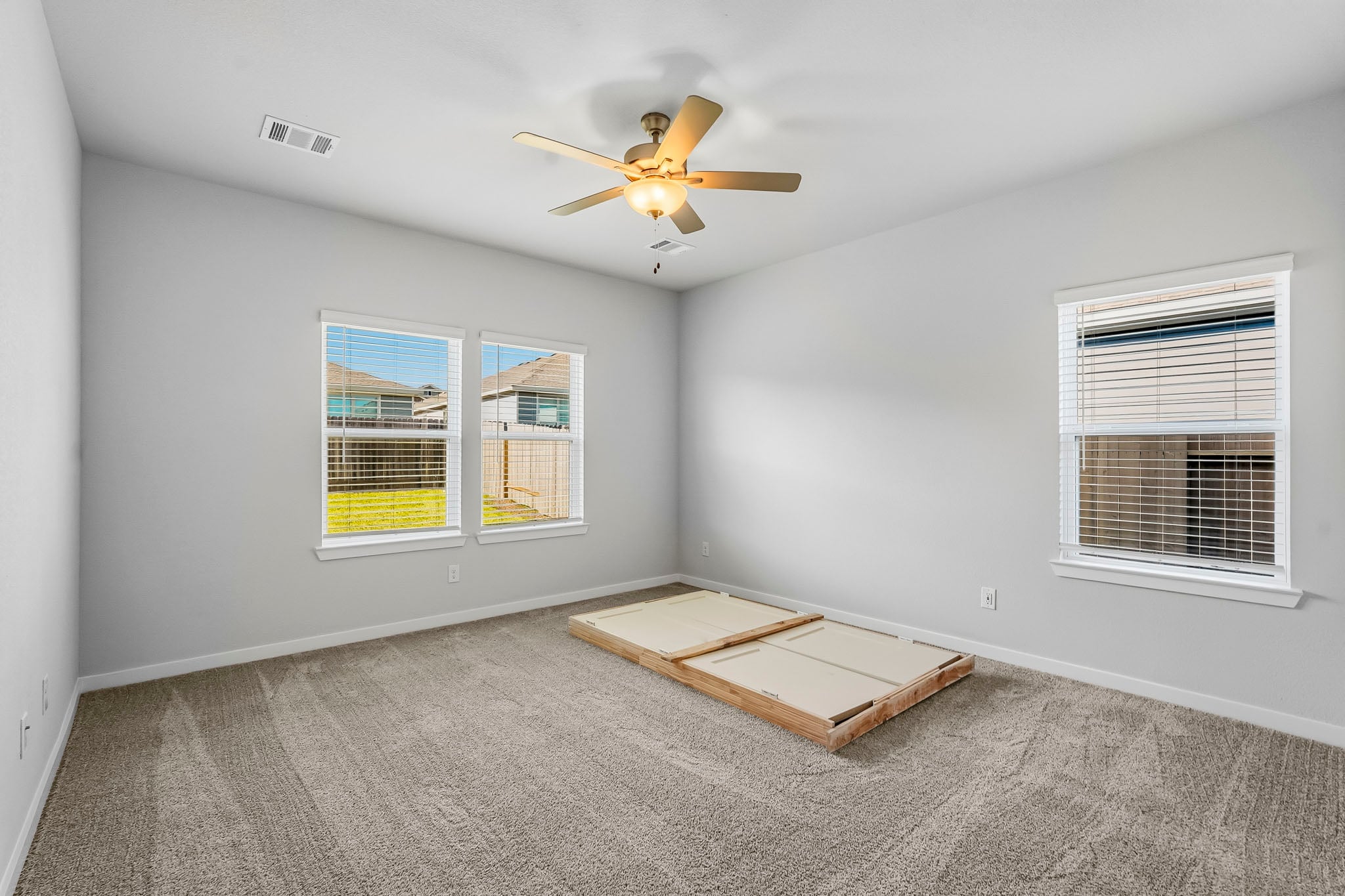 A room with a ceiling fan and a wood box with a window.