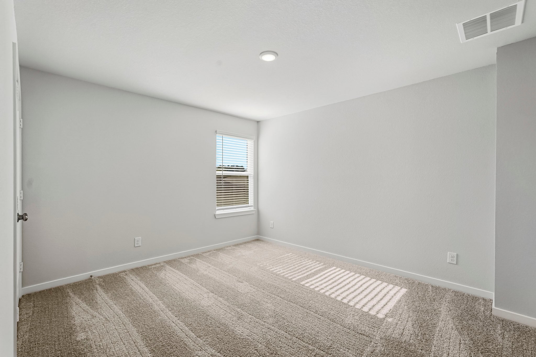A room with a carpet and a window.