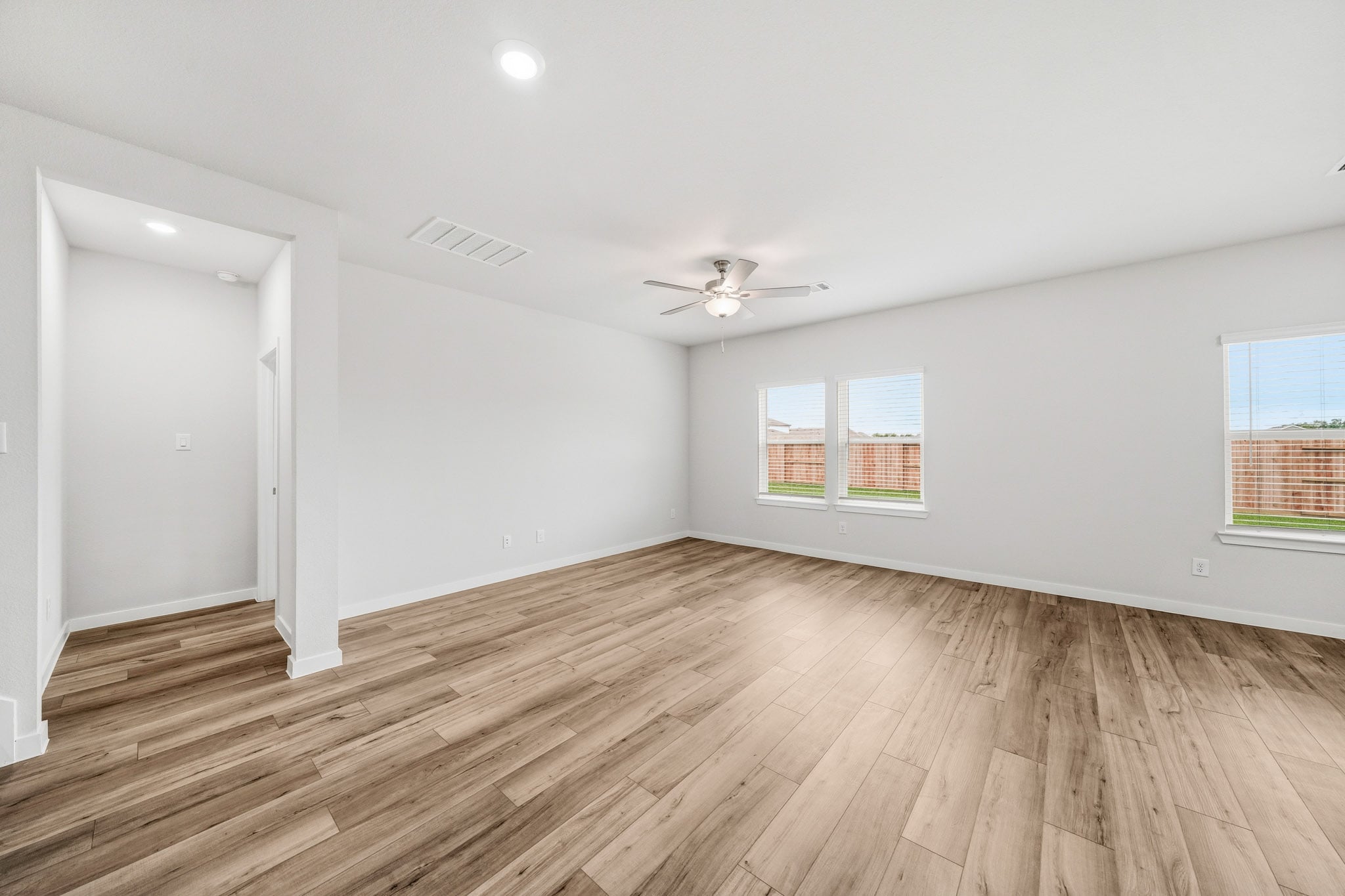 A room with a wood floor and a ceiling fan.