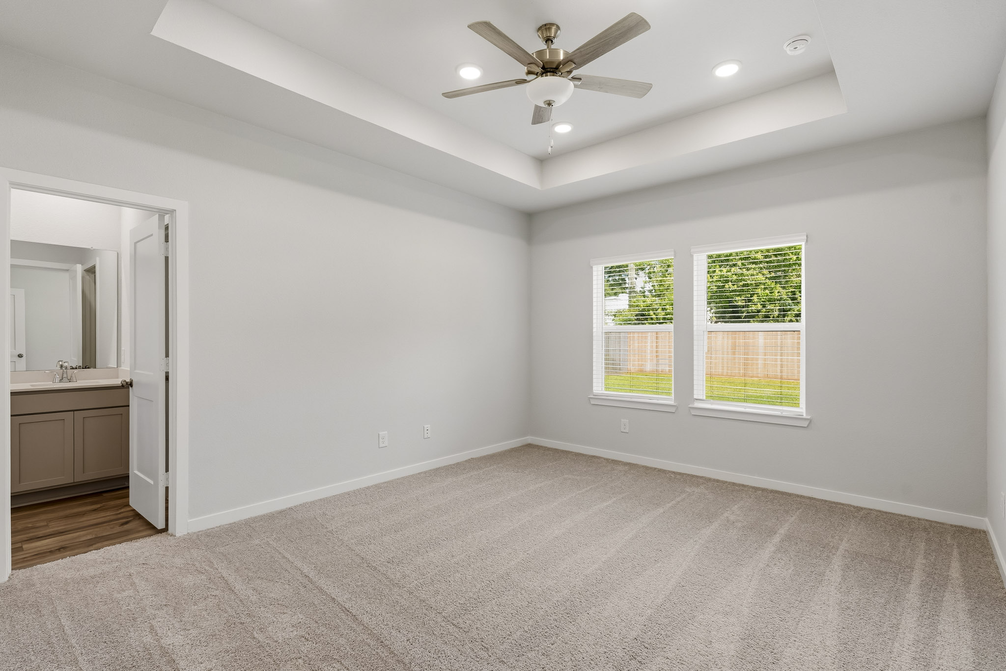 A large empty room with a ceiling fan and a window.