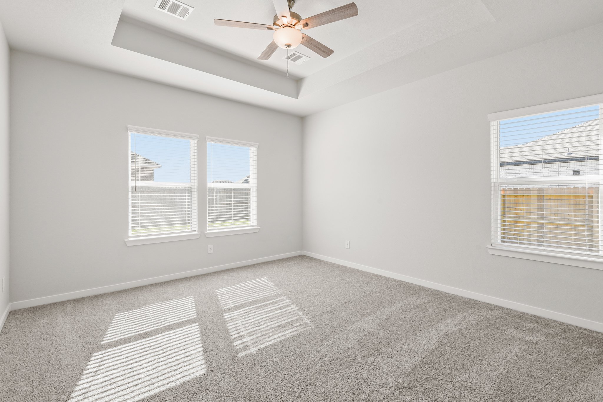 A room with a ceiling fan and windows.