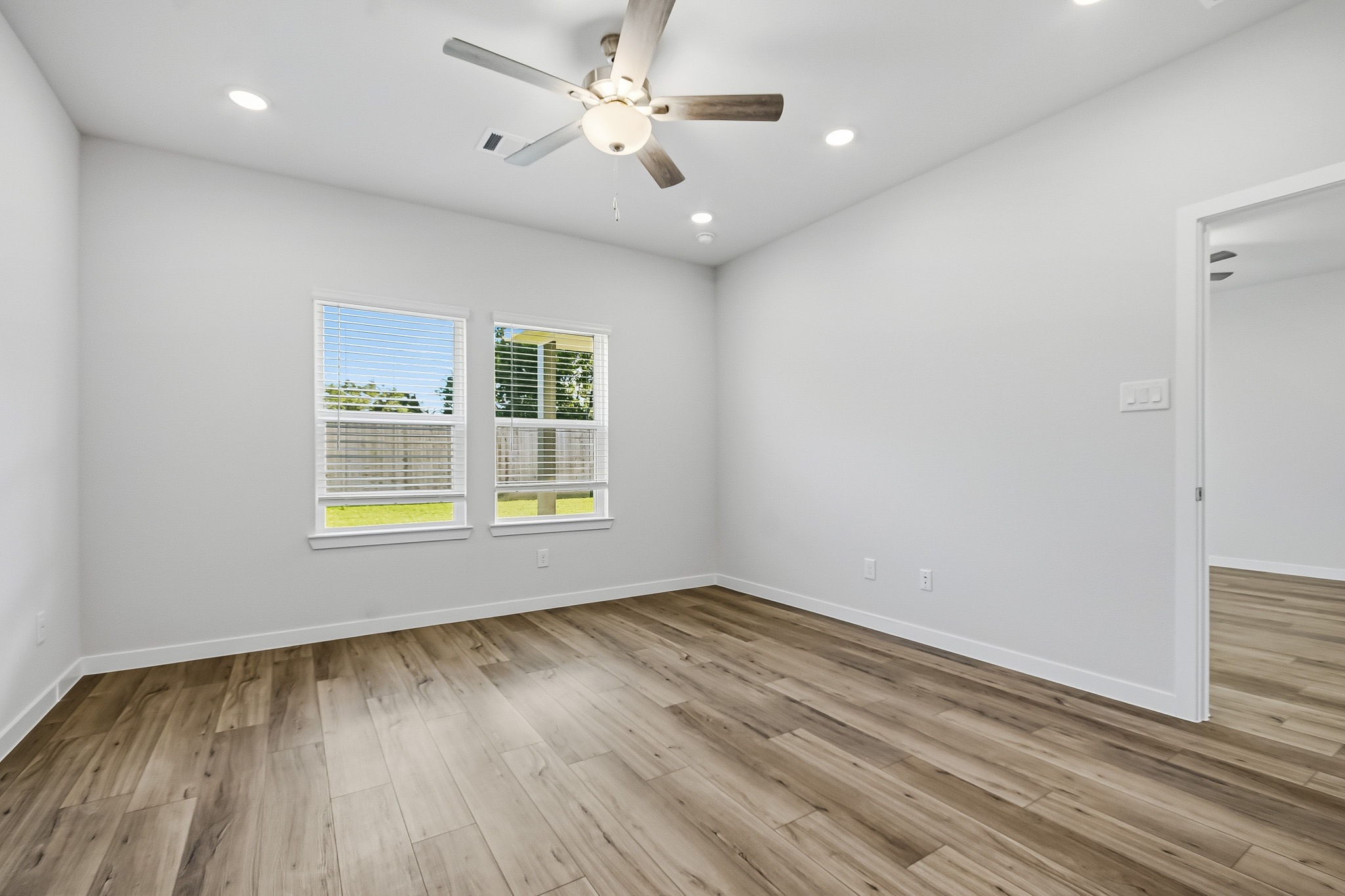 A room with a wood floor and a ceiling fan.