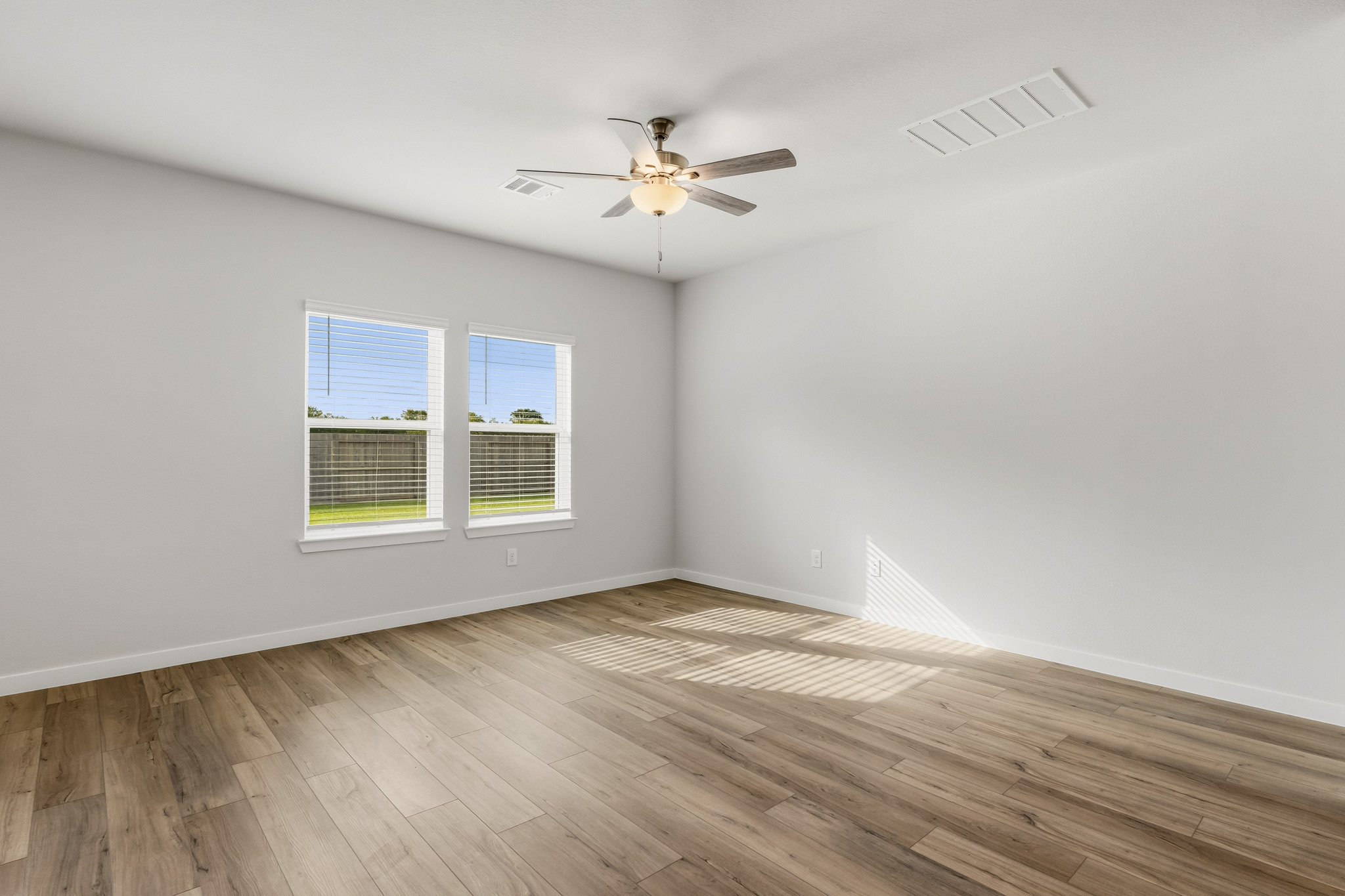 A room with a ceiling fan and a wood floor.