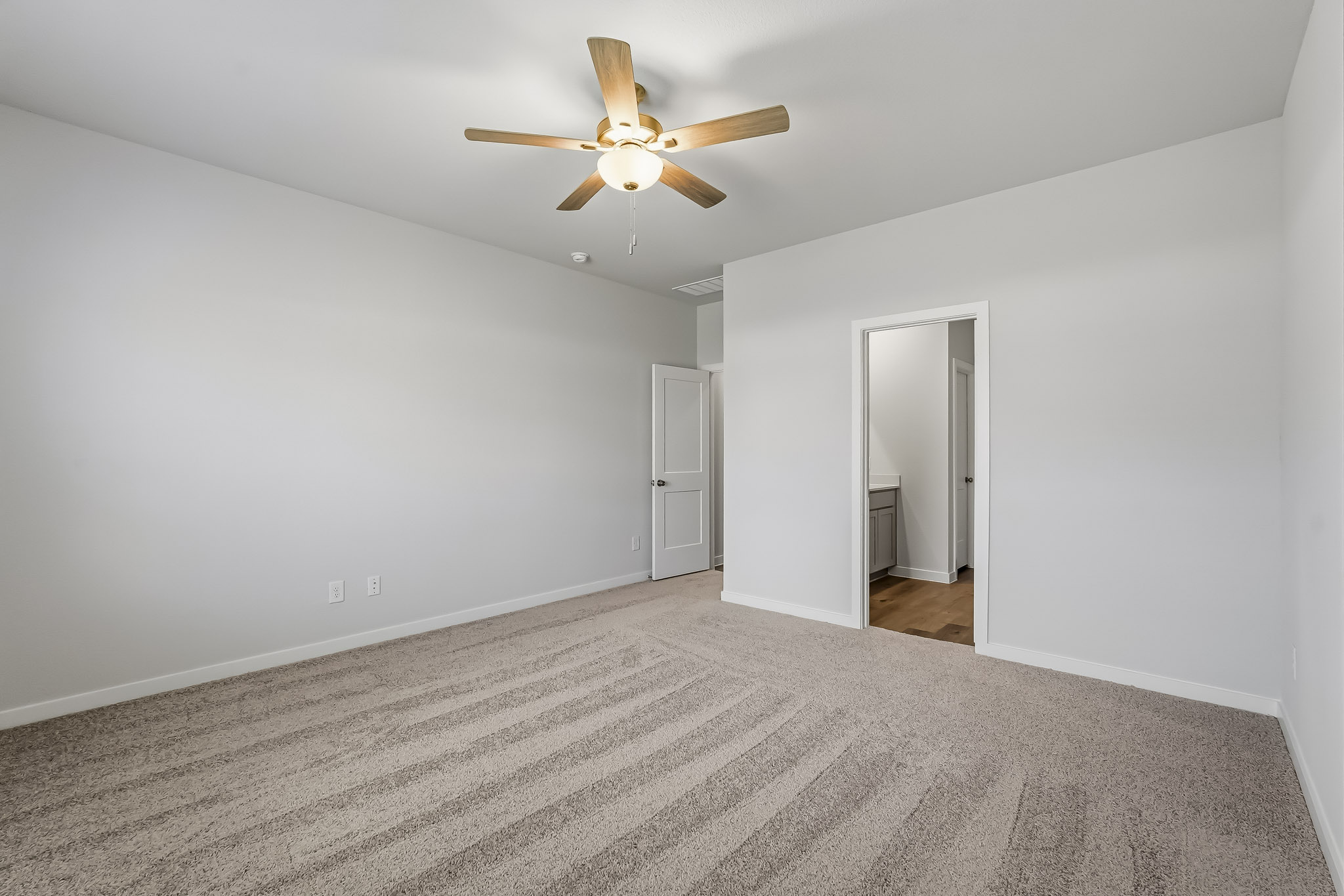 A room with a ceiling fan and a carpet.