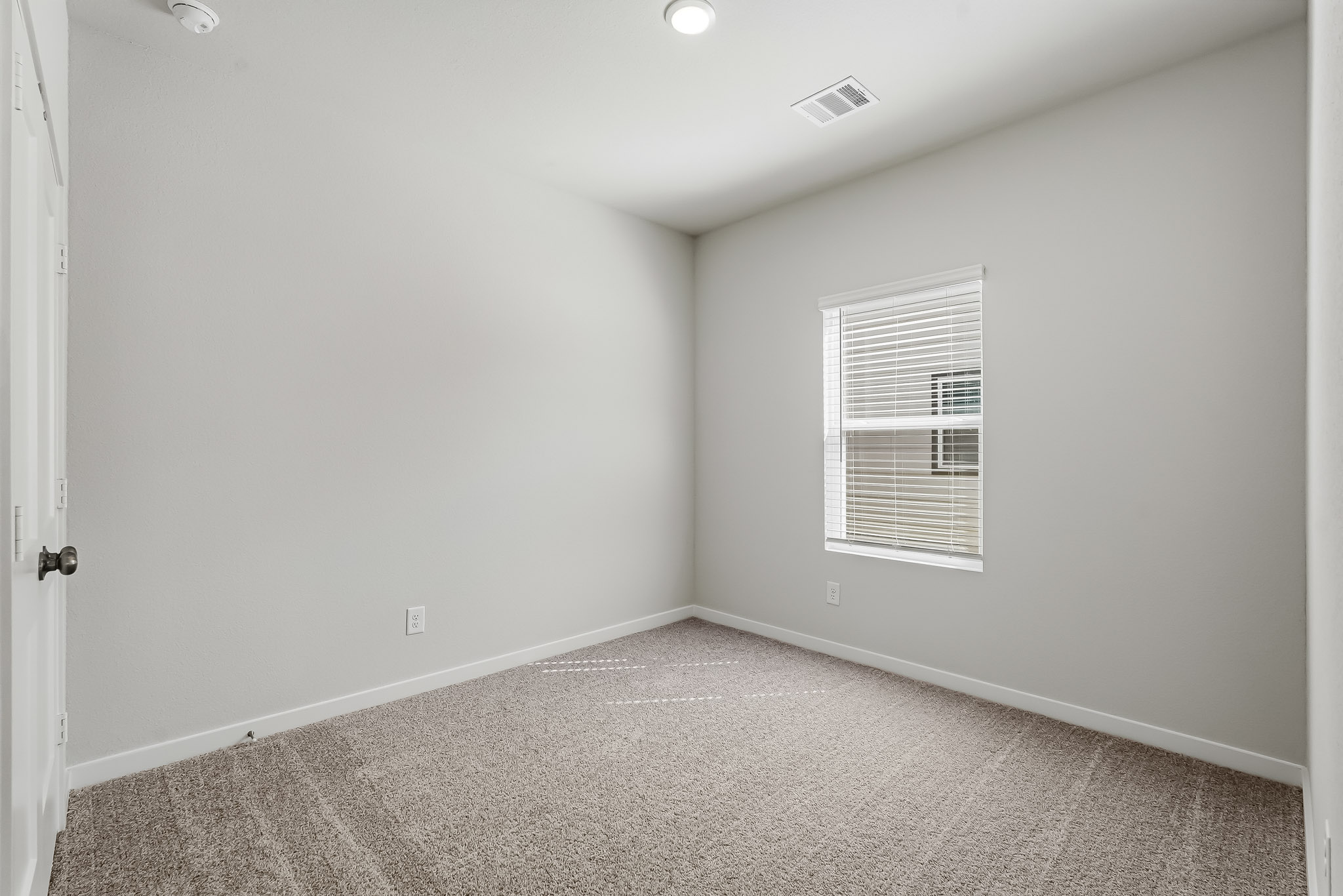 A room with a carpet and a door.
