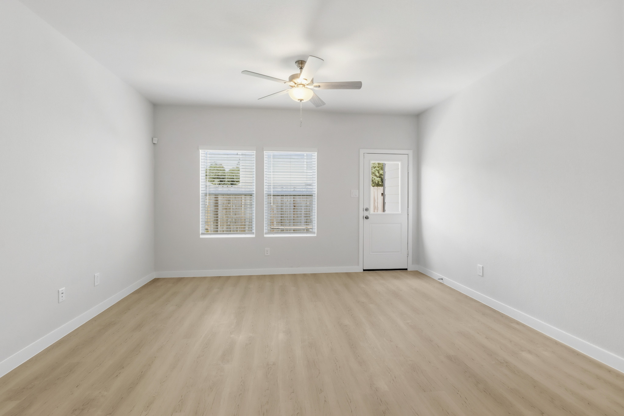 A room with a ceiling fan and a wood floor.