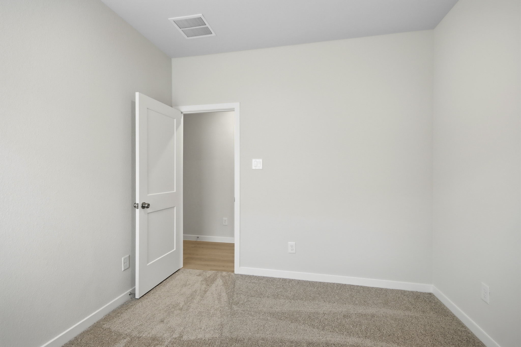 A room with a carpet and a door.