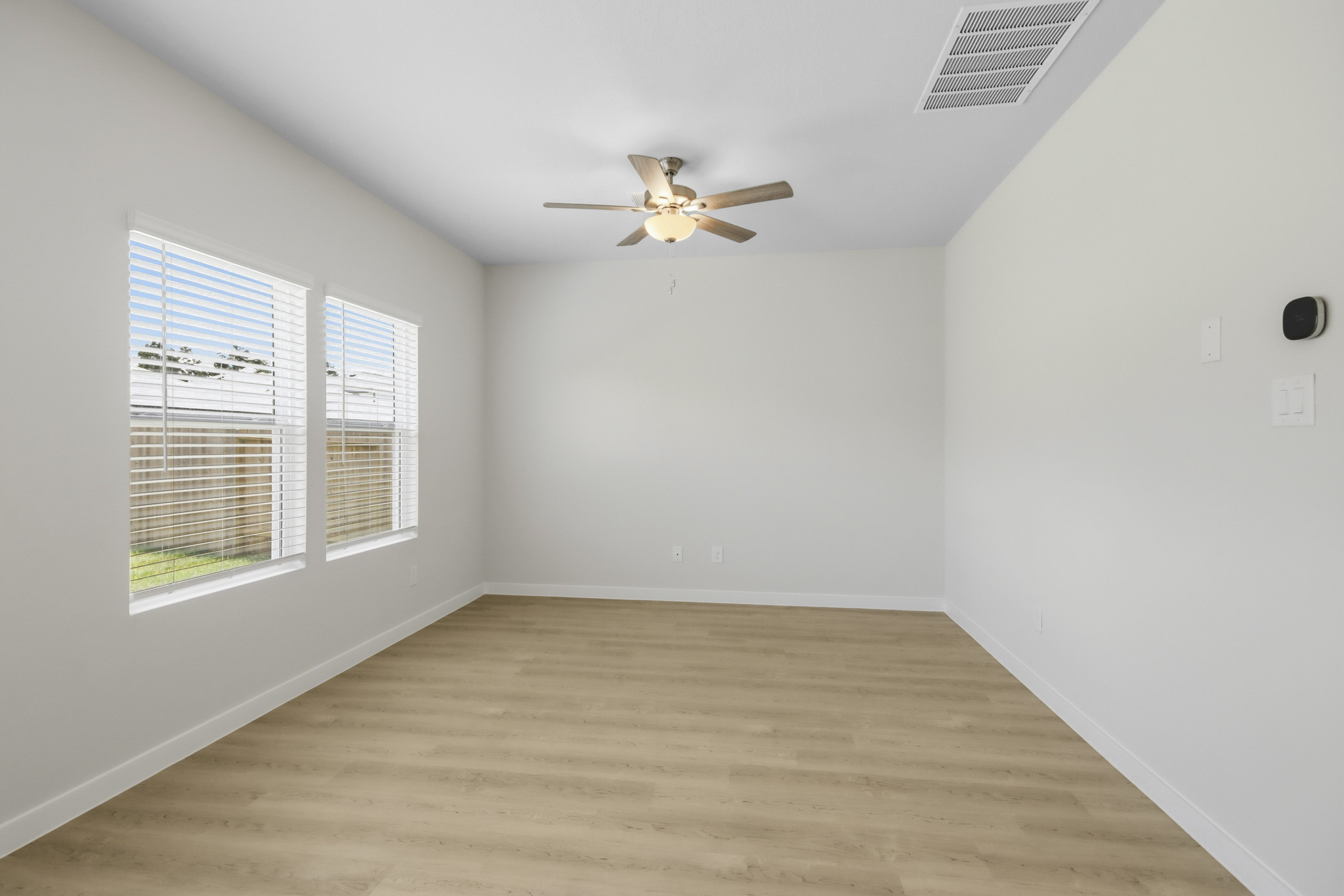 A room with a ceiling fan and a wood floor.