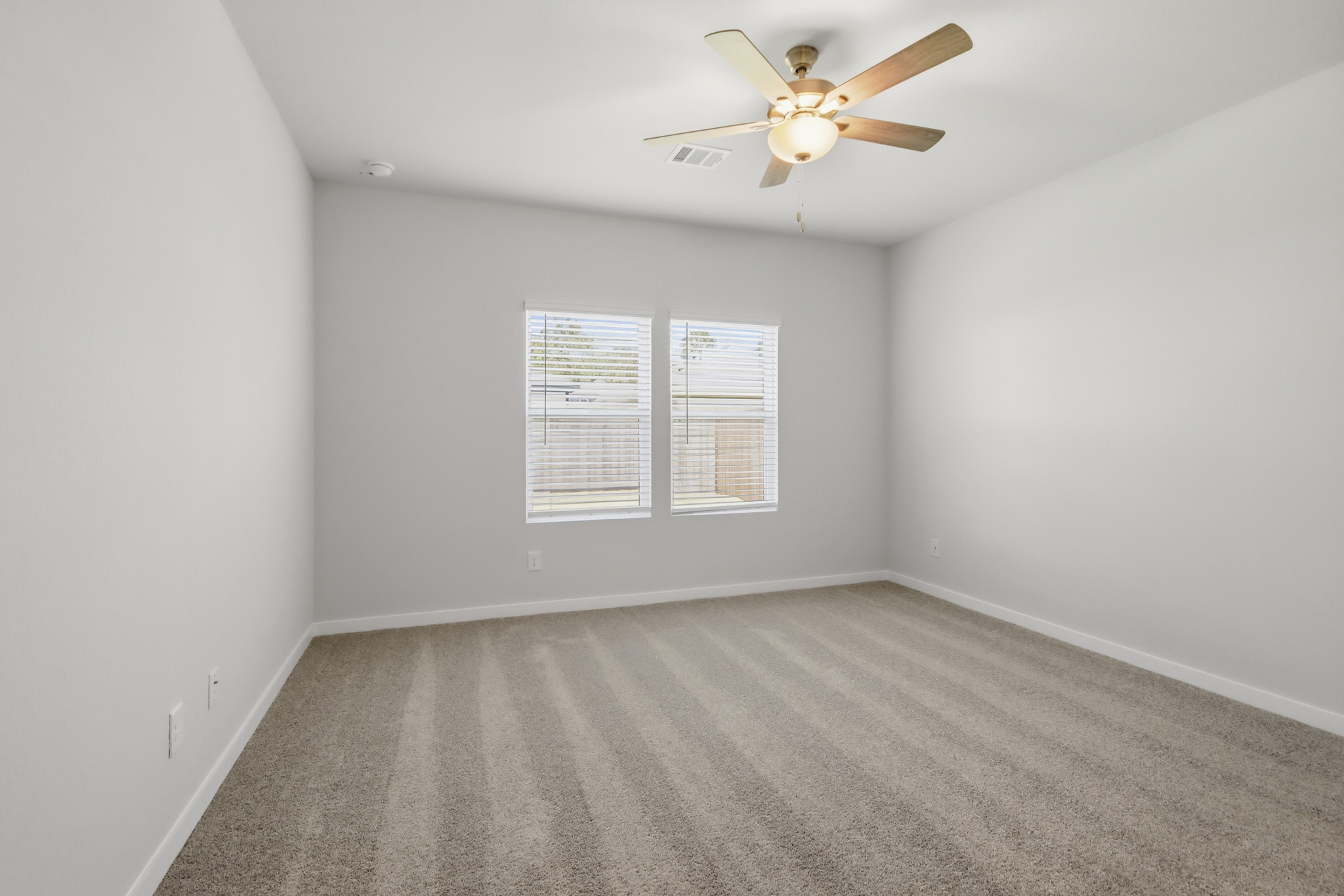 A room with a ceiling fan and a carpet.