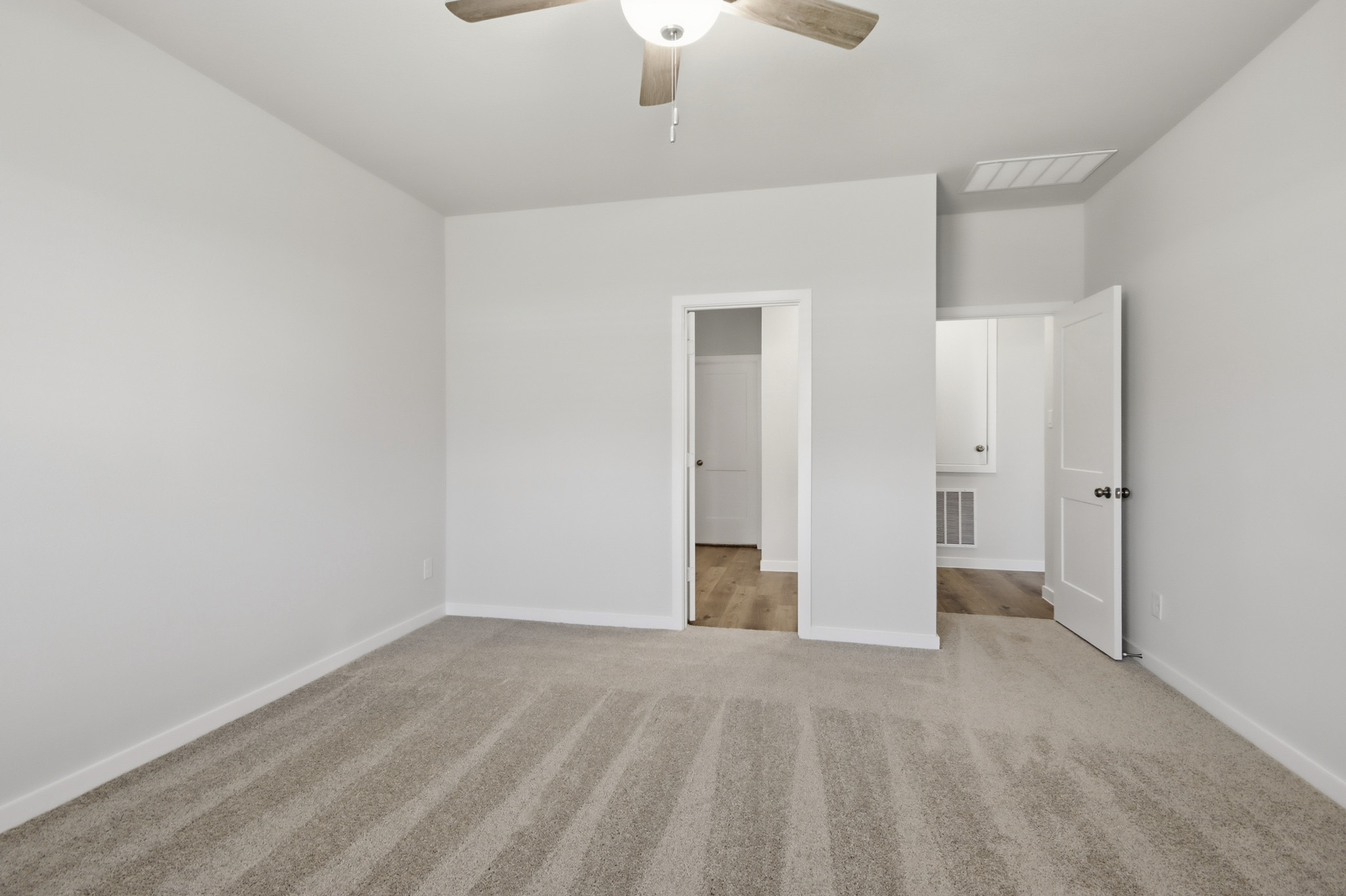 A room with white walls and a ceiling fan.