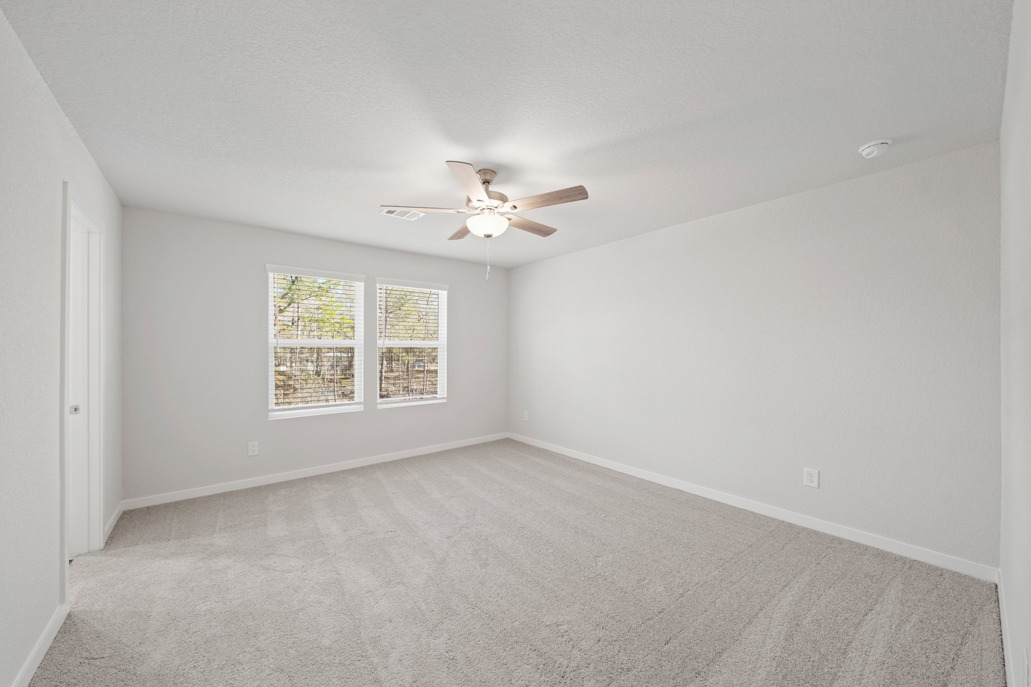 A room with a ceiling fan and a window.