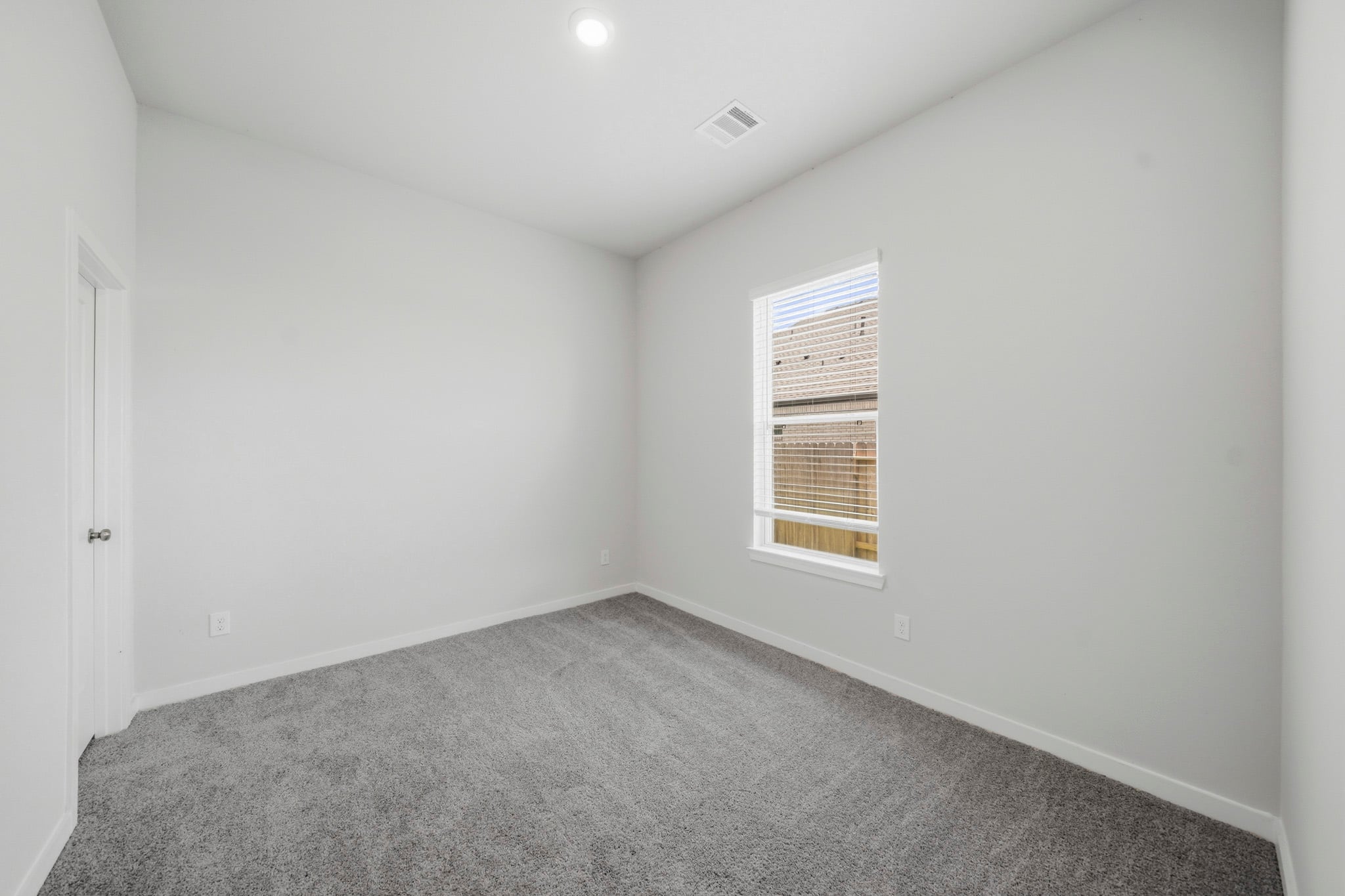 A room with a window and carpet.