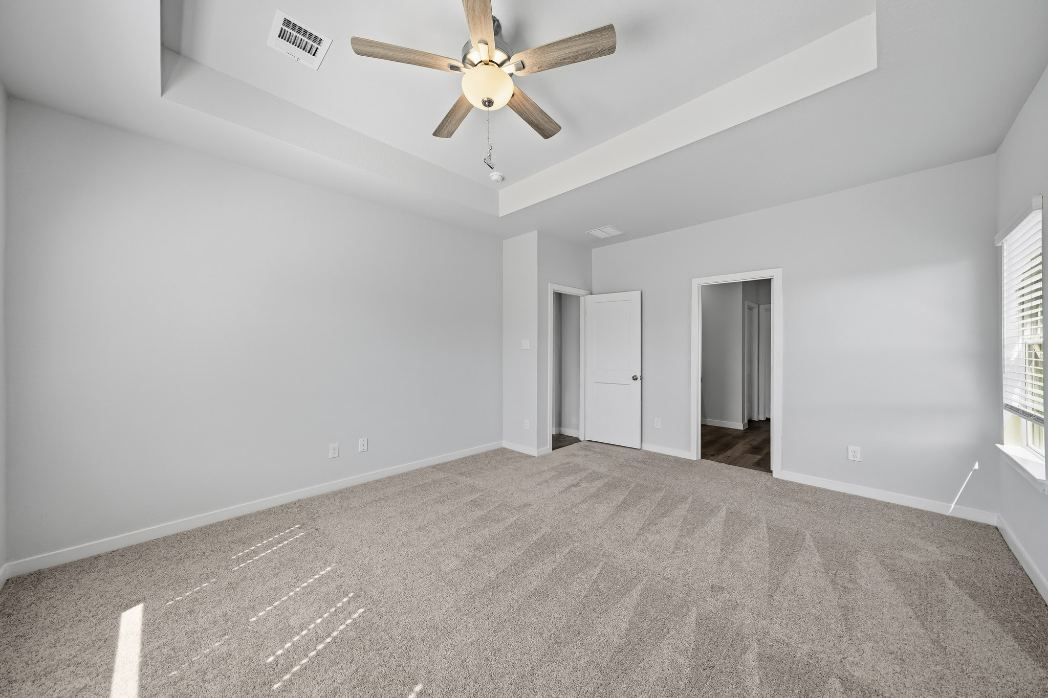 A room with a ceiling fan and carpet.