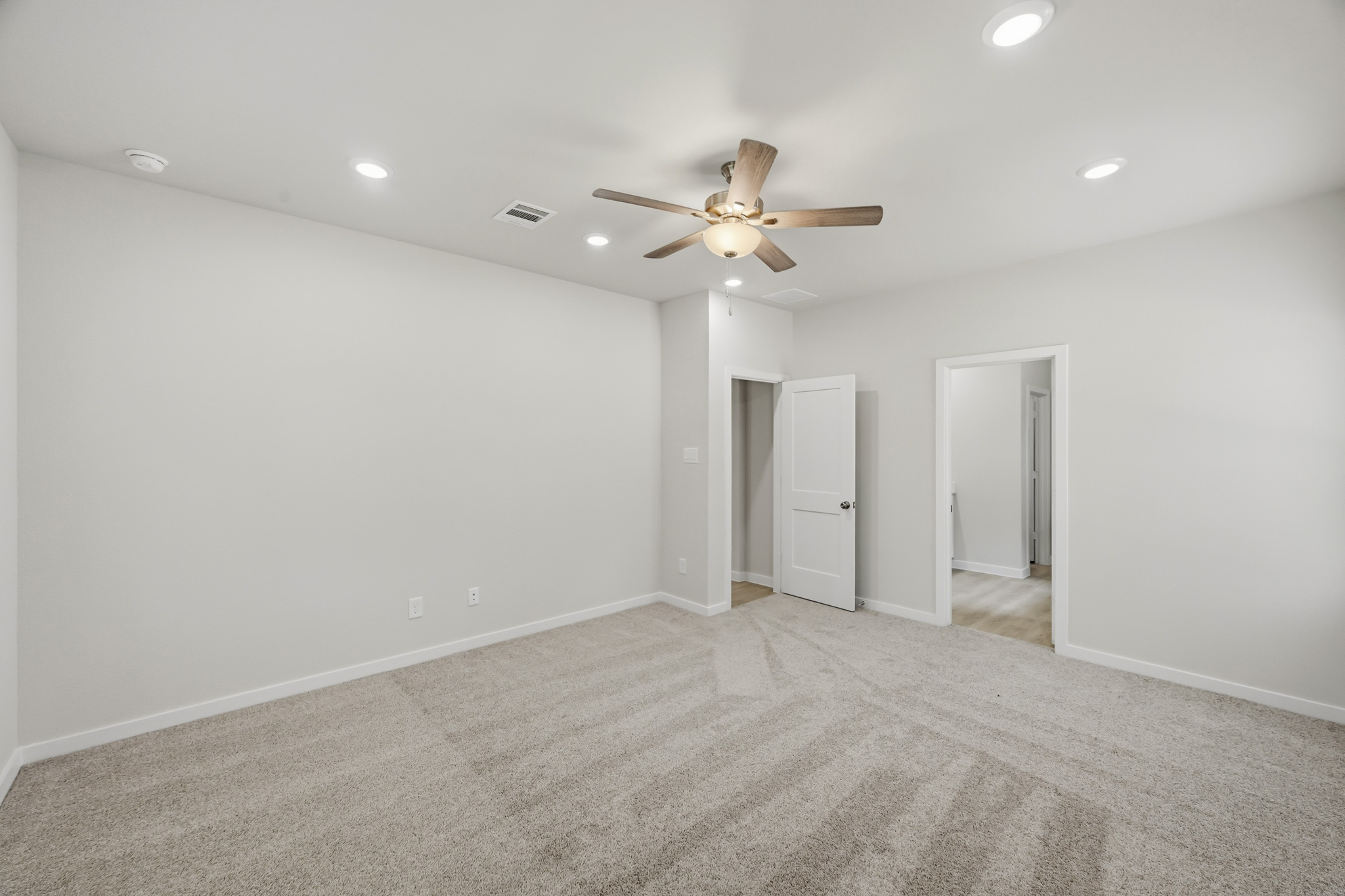 A room with a ceiling fan and a carpet.