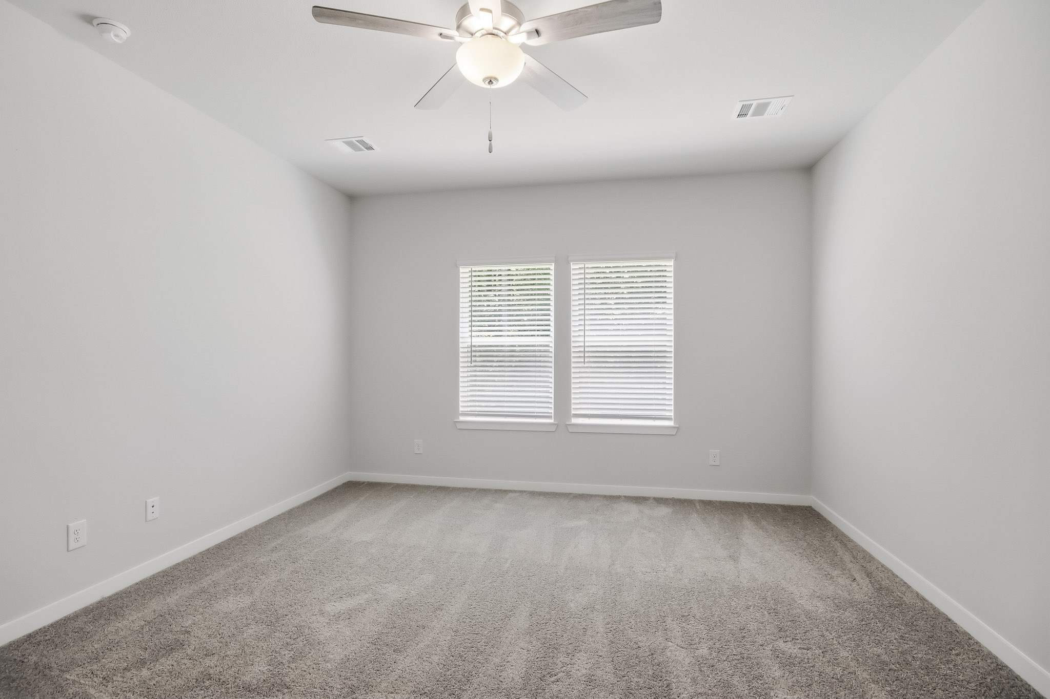A room with a ceiling fan and a carpet.