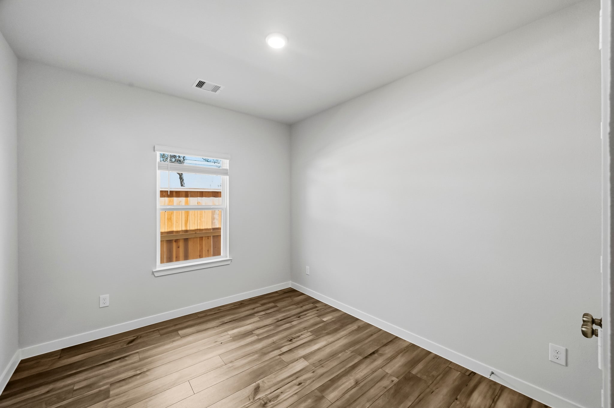 A room with a wood floor and a window.