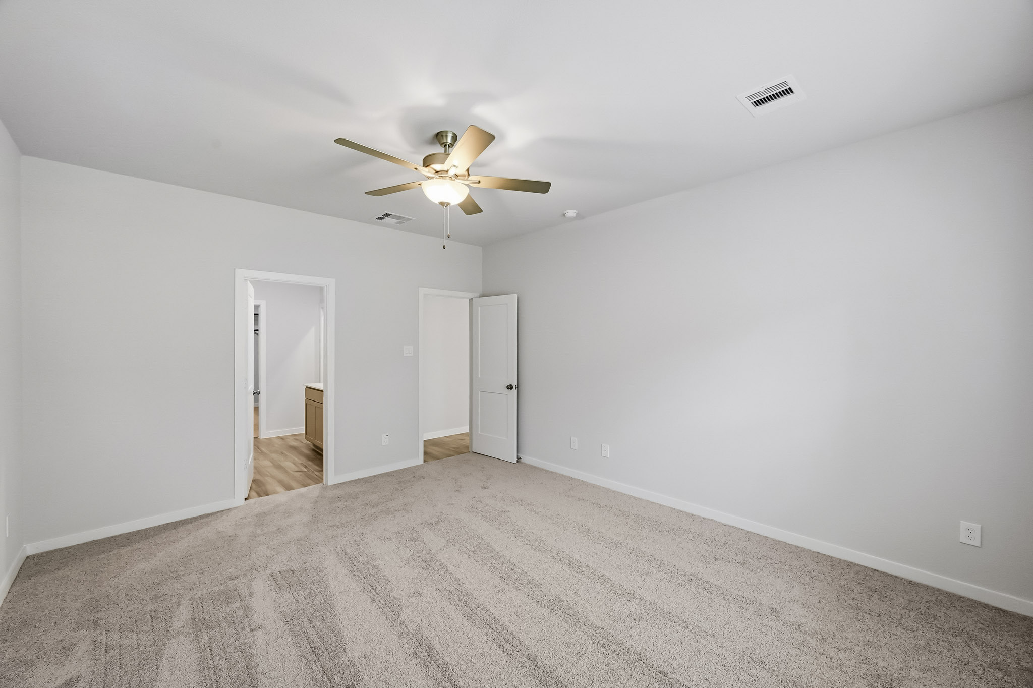 A room with a ceiling fan and a door.