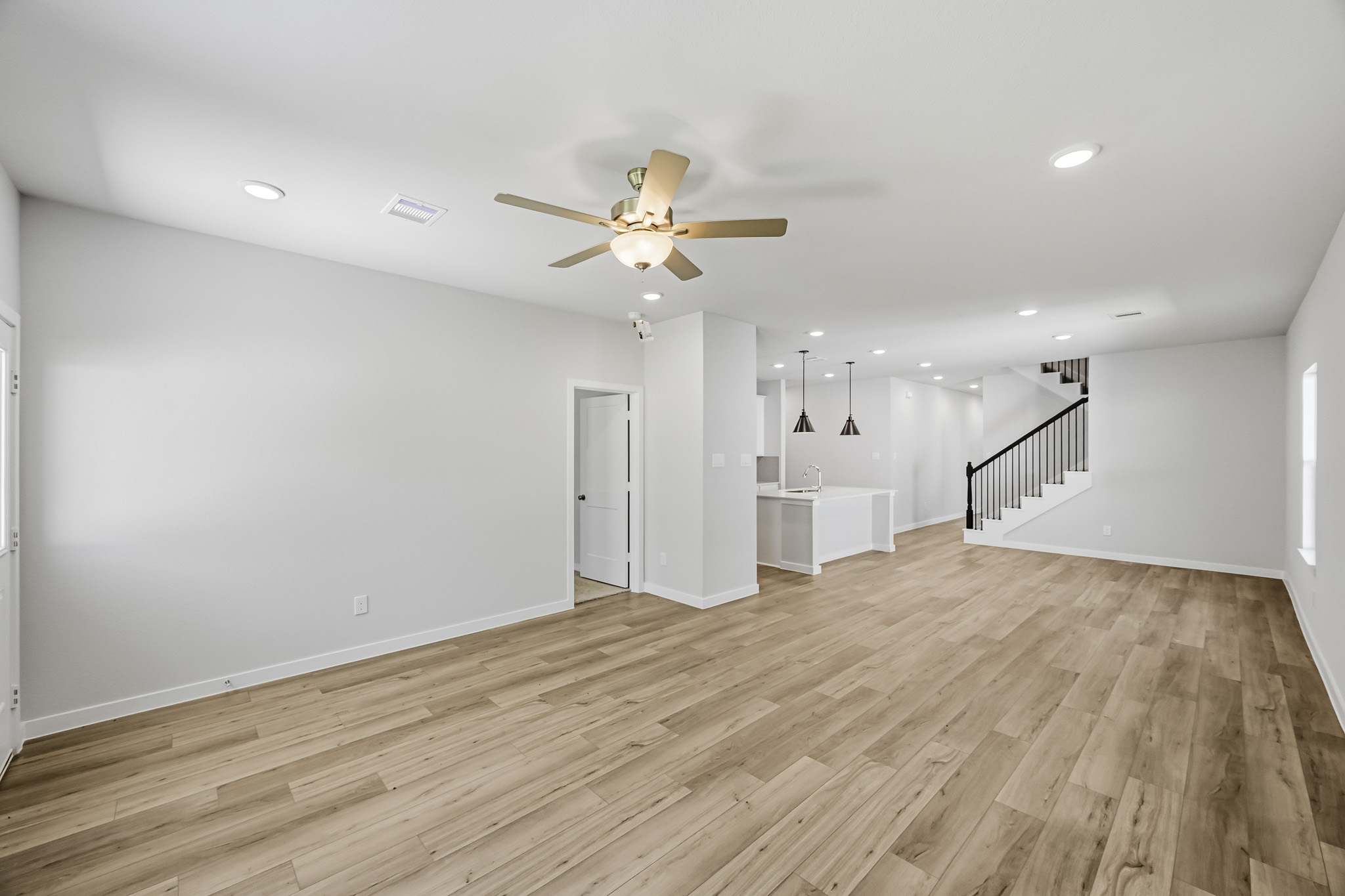 A large empty room with a wood floor and a ceiling fan.