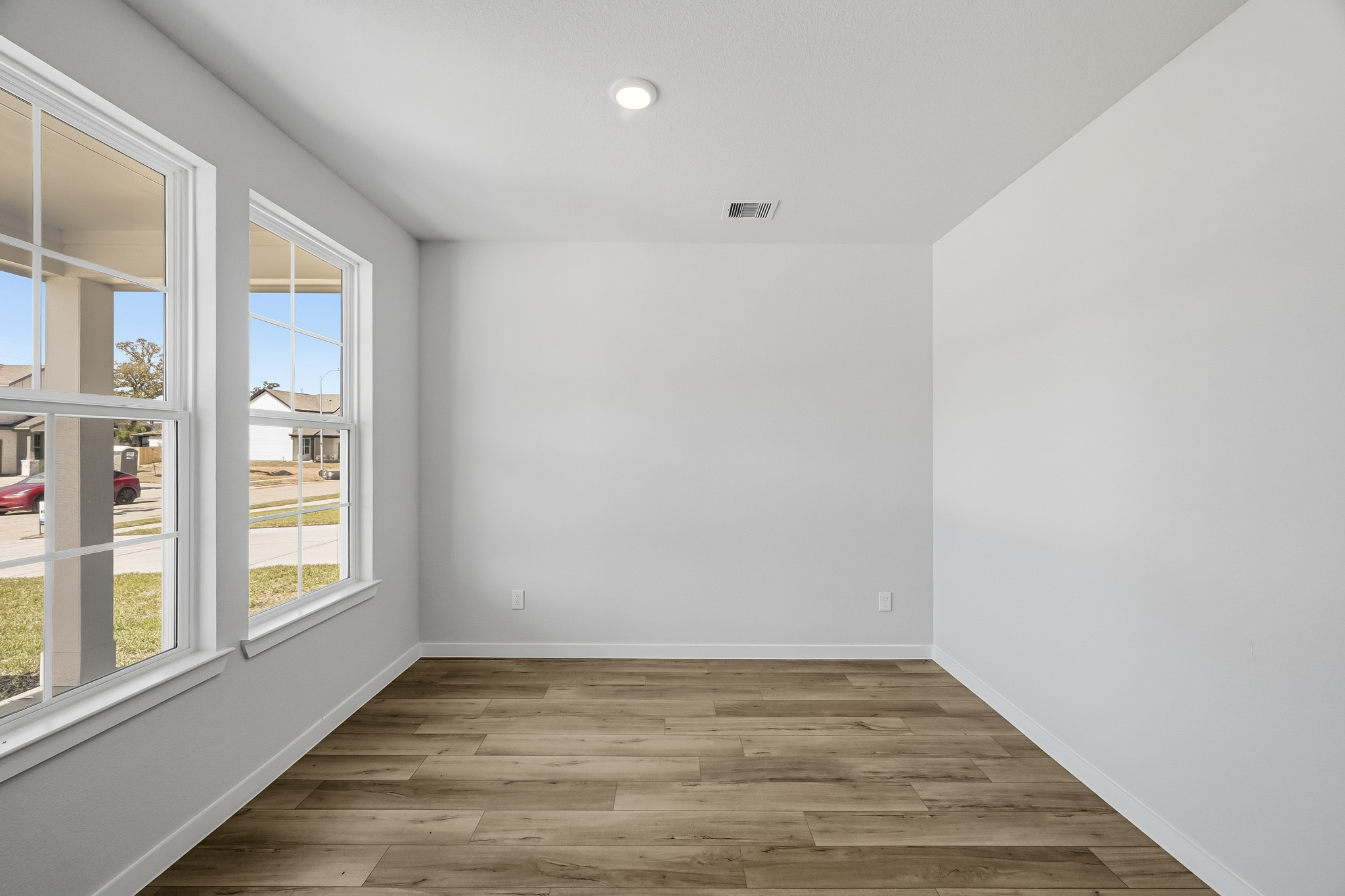 A room with windows and a wood floor.