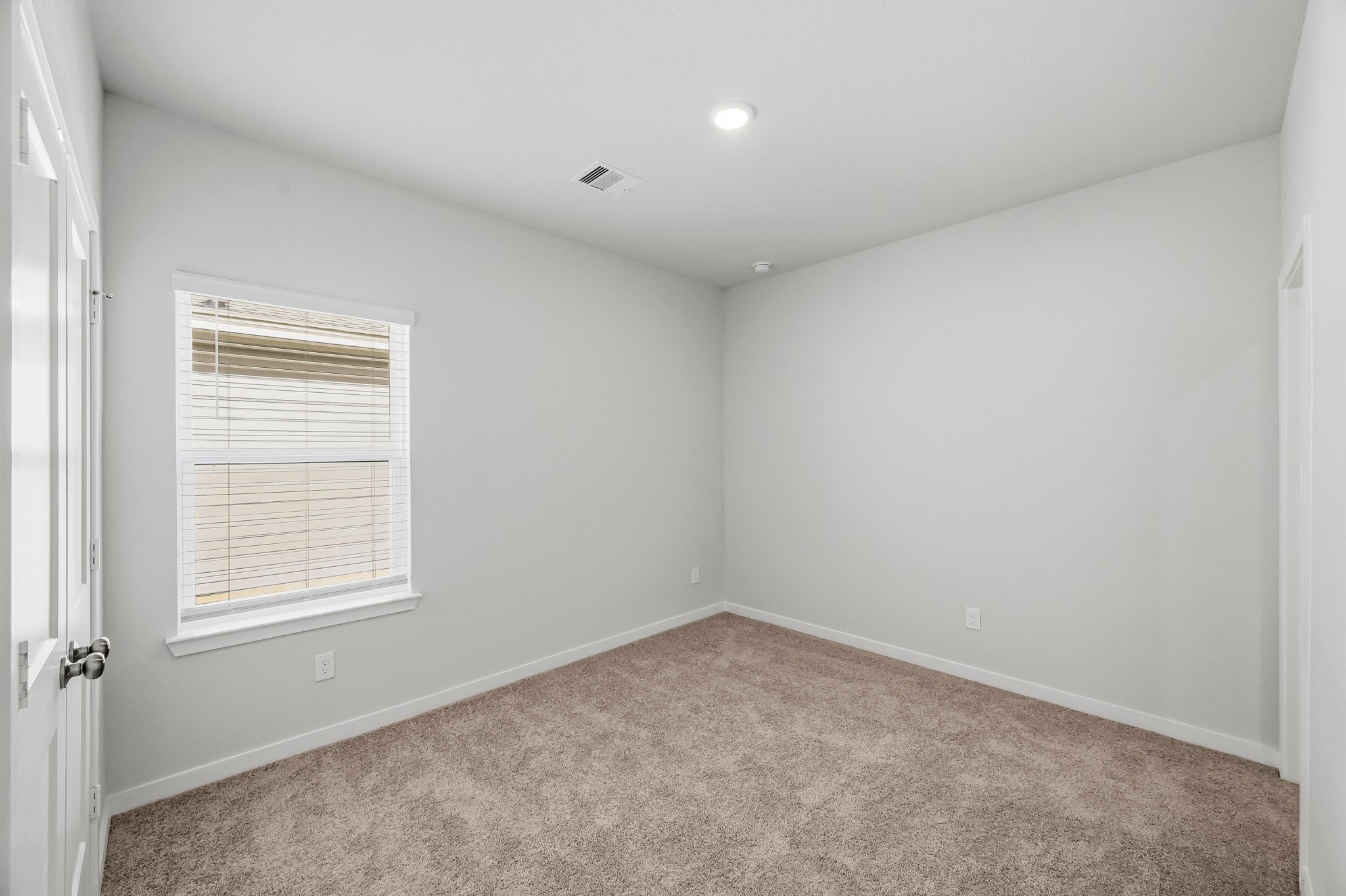 A room with a carpet and a window.