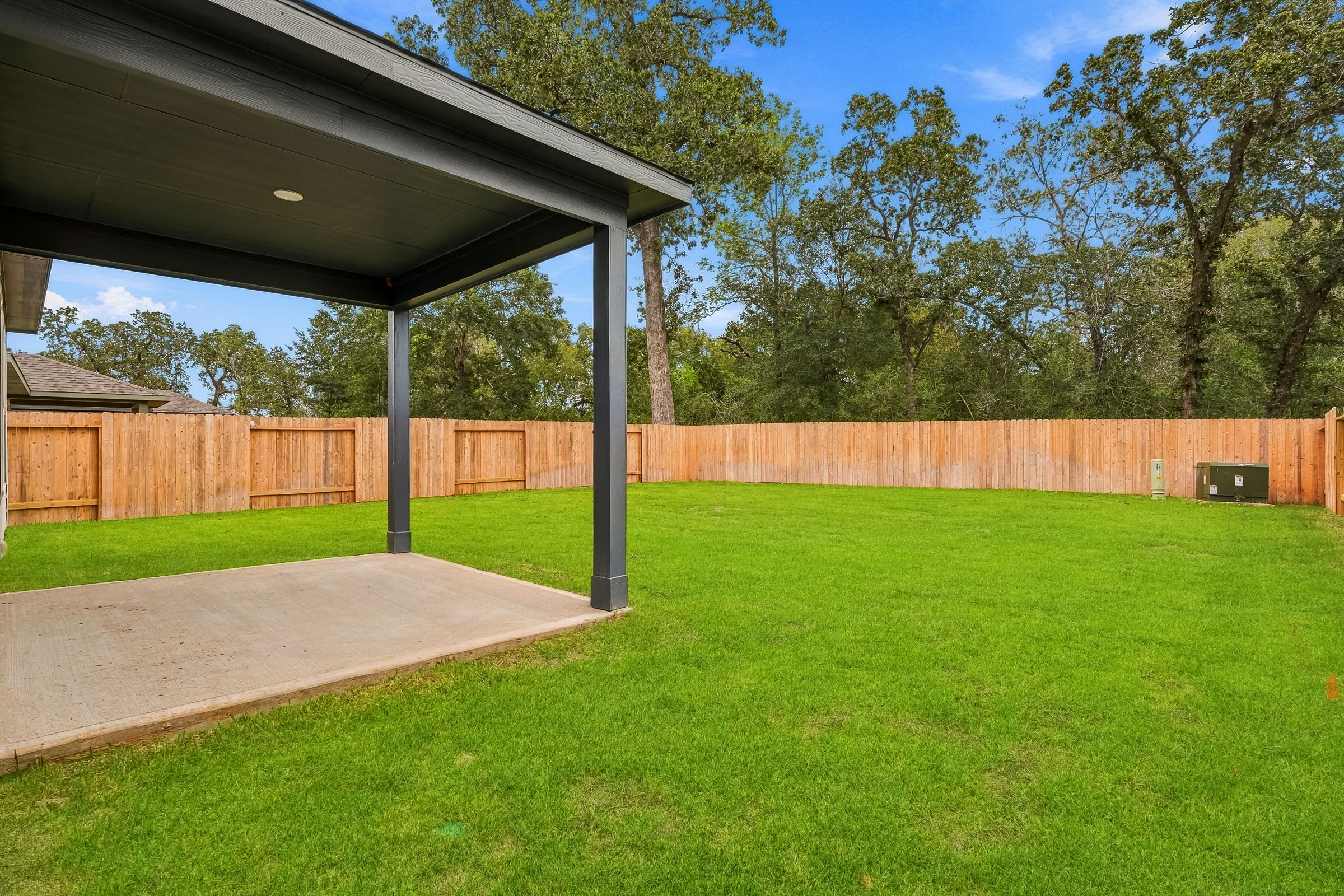 A backyard with a fence and a covered area.