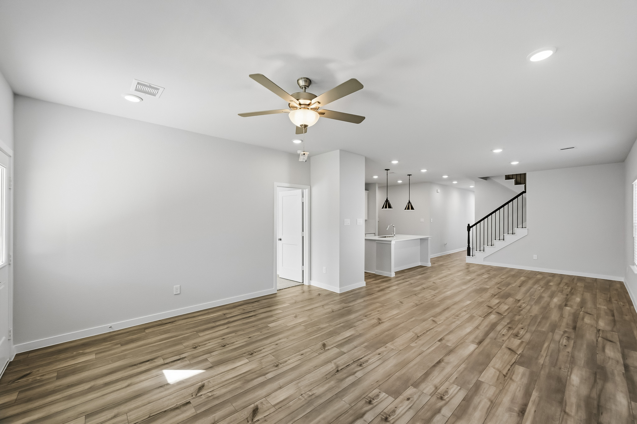 A large empty room with a wood floor and a ceiling fan.