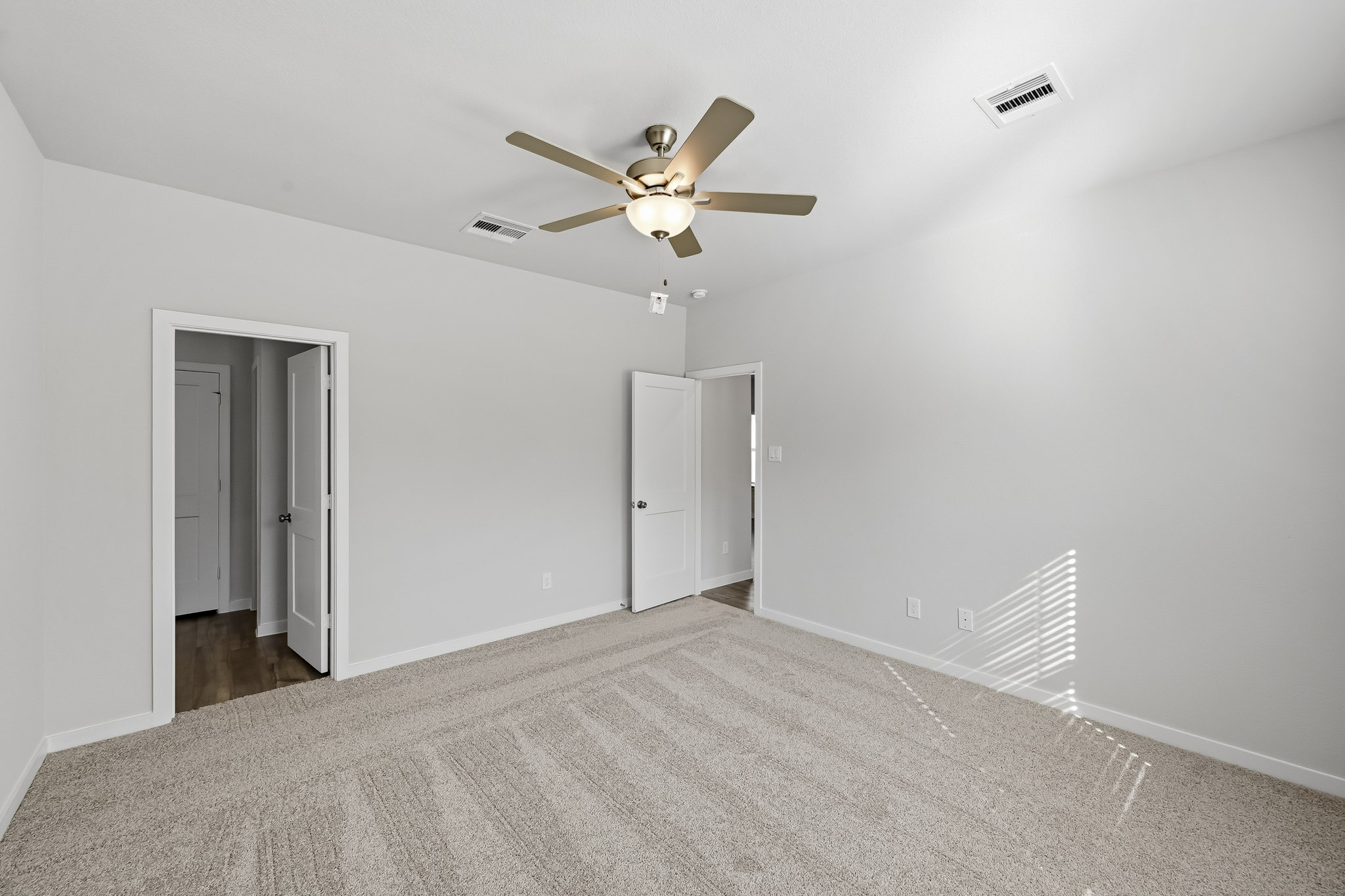 A room with a ceiling fan and white walls.