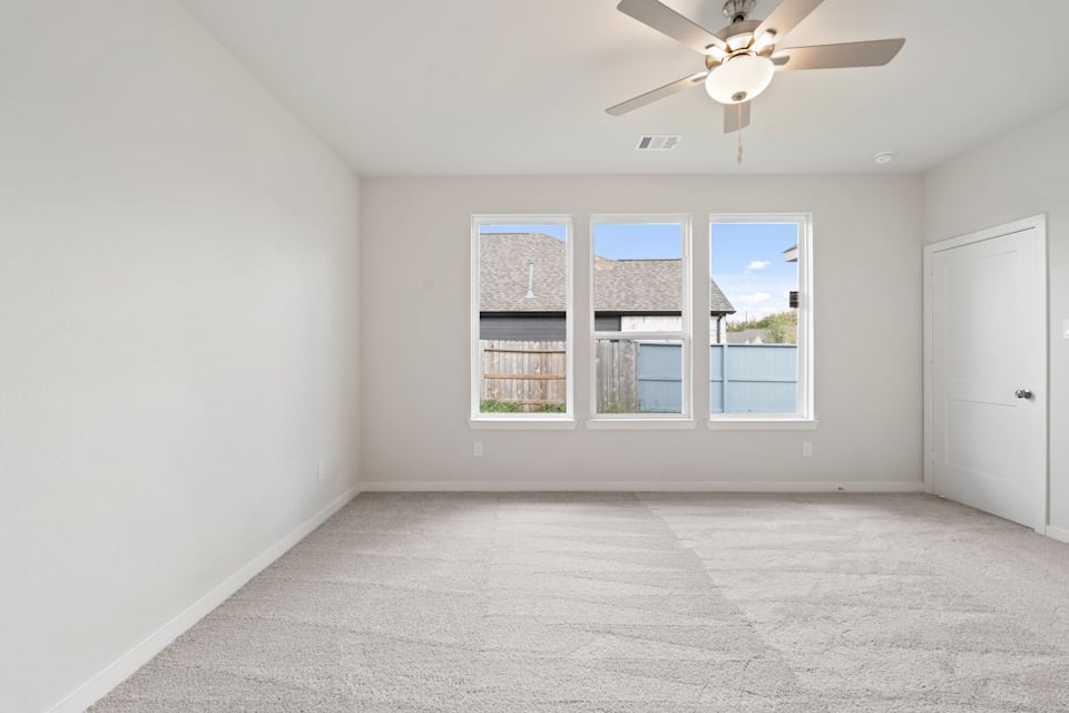 A room with a ceiling fan and a window with a view of the ocean.