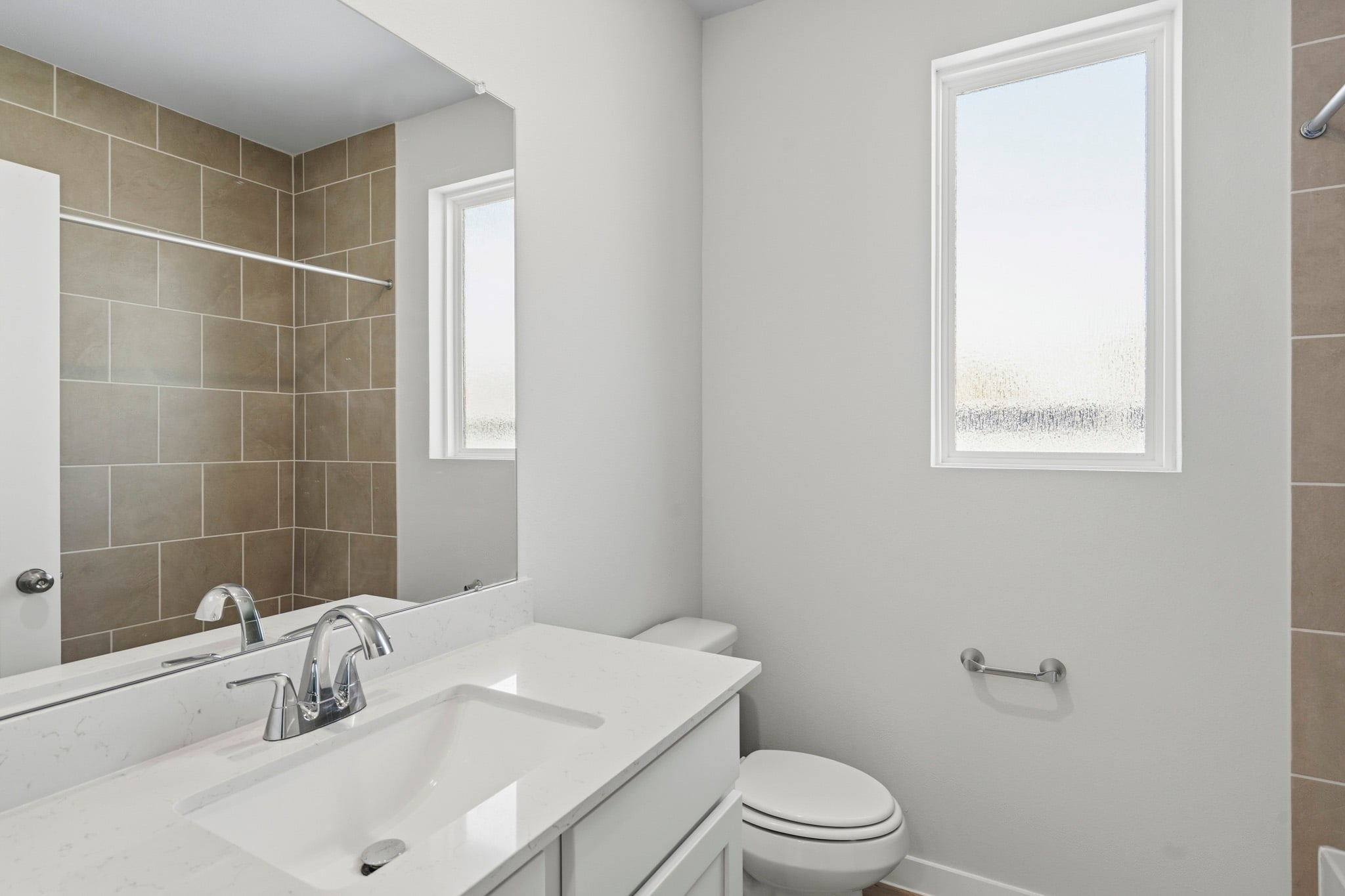 A bathroom with a sink toilet and mirror.