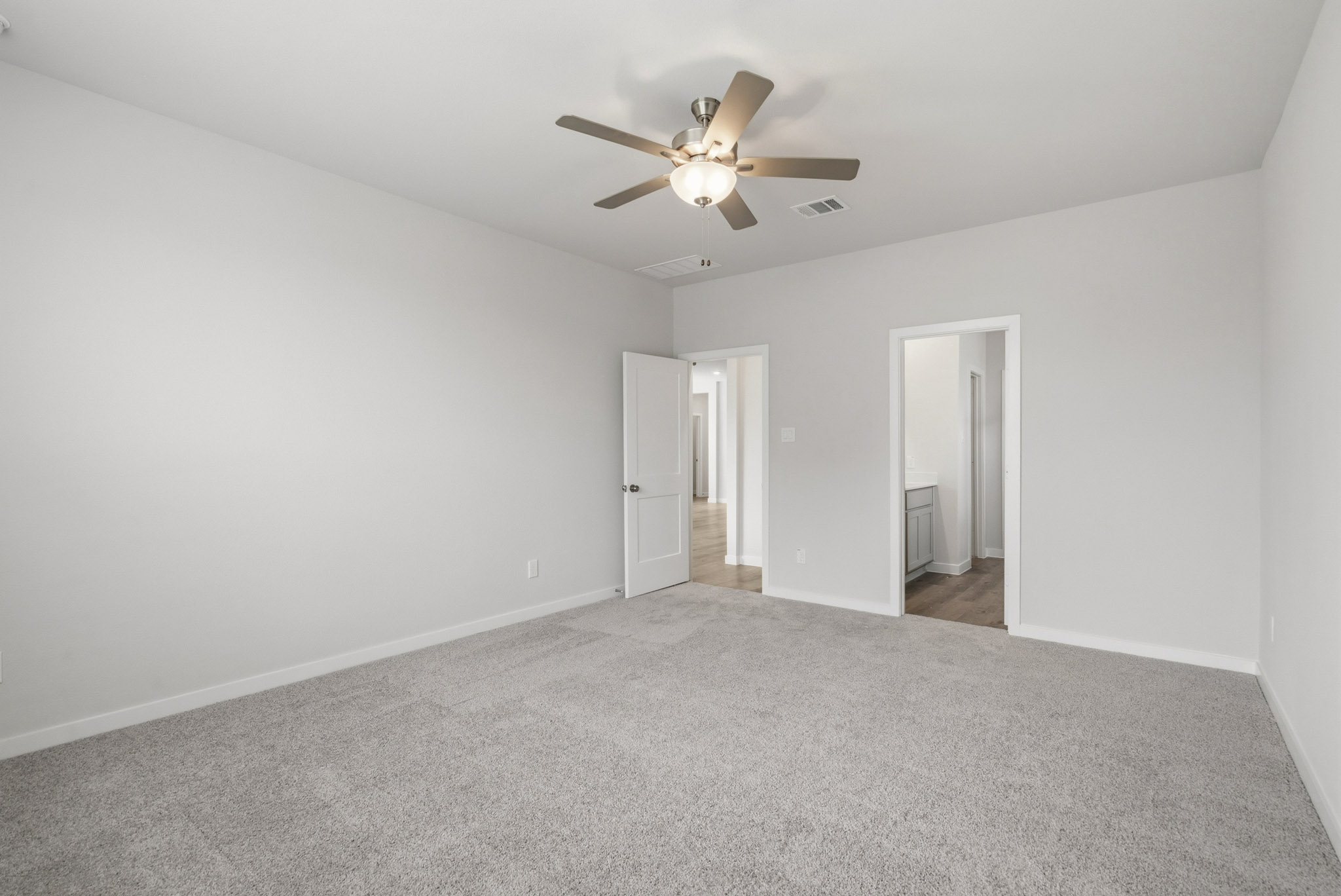 A room with a ceiling fan and a carpet.