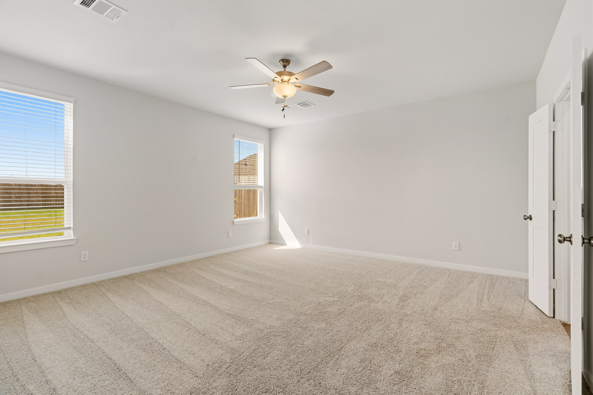 A room with a ceiling fan and a carpet.