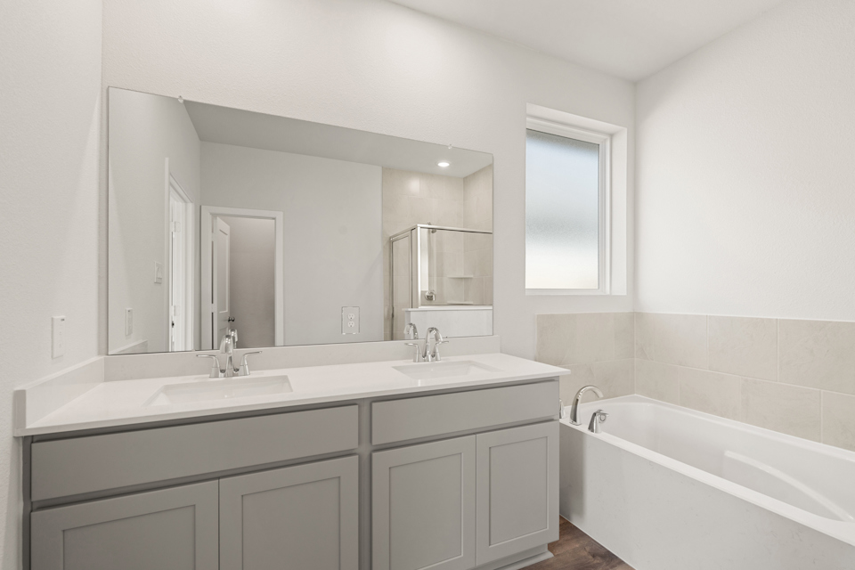 A bathroom with a tub sink and mirror.