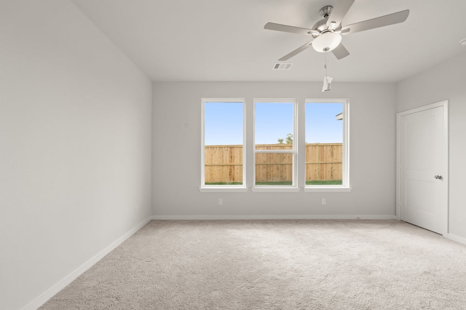 A room with a ceiling fan and a window with a light on the ceiling.