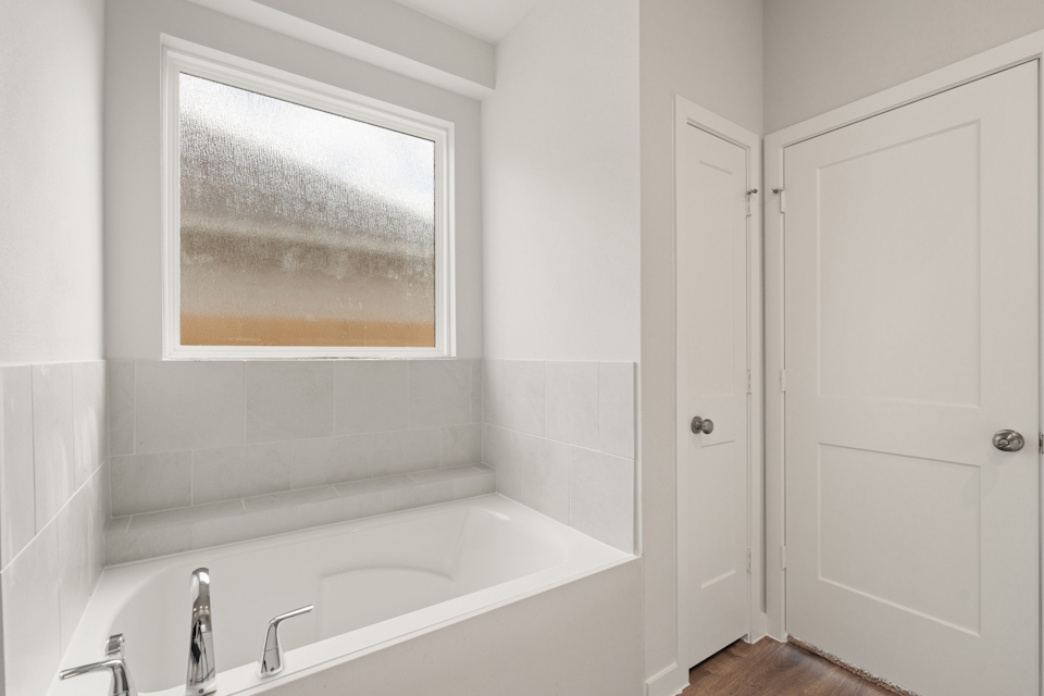 A bathtub and a window in a bathroom.