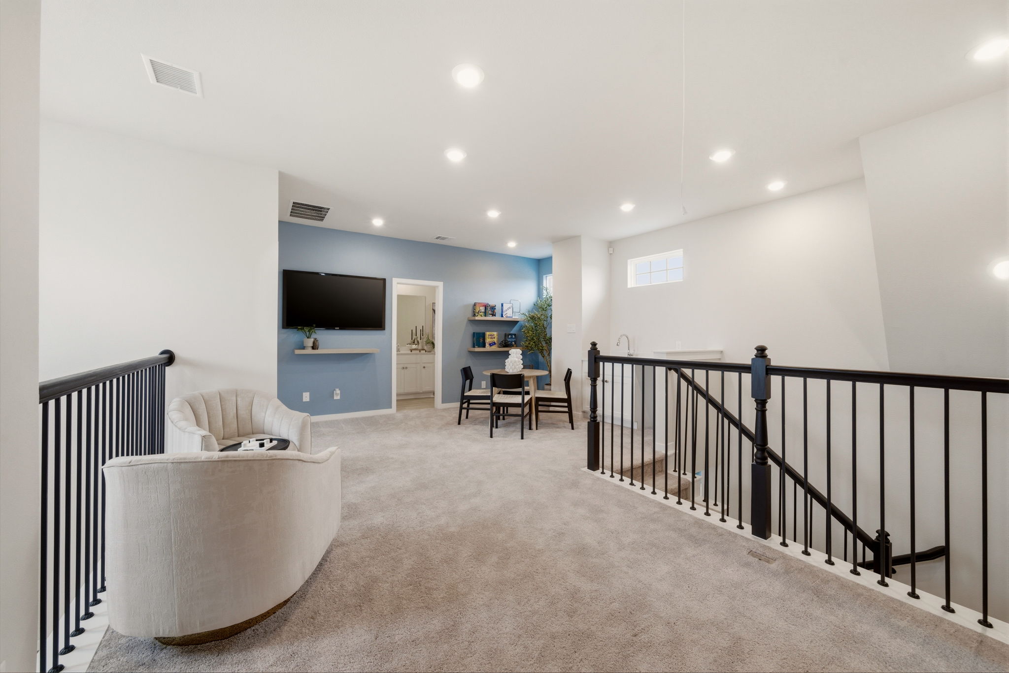 A large white room with a black railing and a white couch.