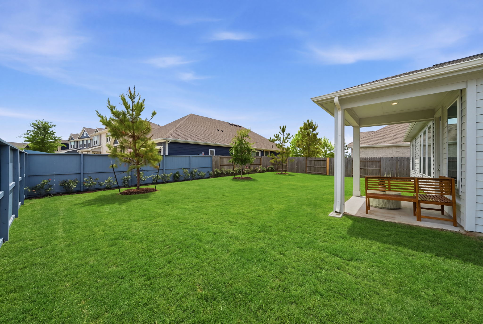 A backyard with a bench and a fence.