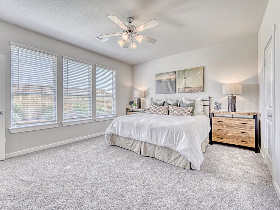A bedroom with a bed and a ceiling fan.