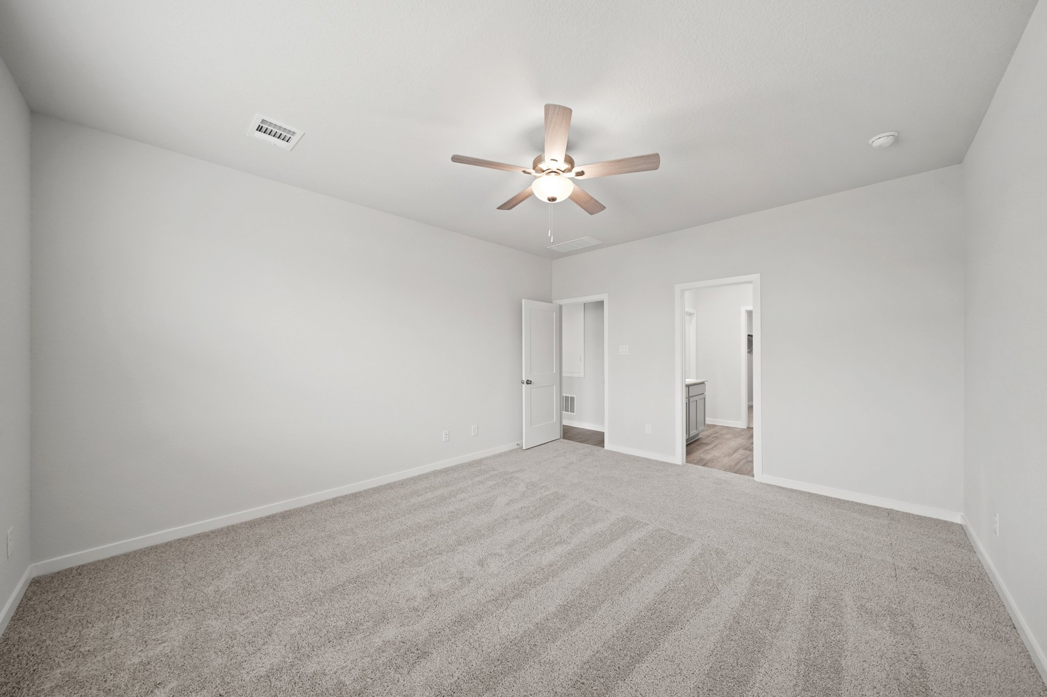A room with a ceiling fan and carpet.