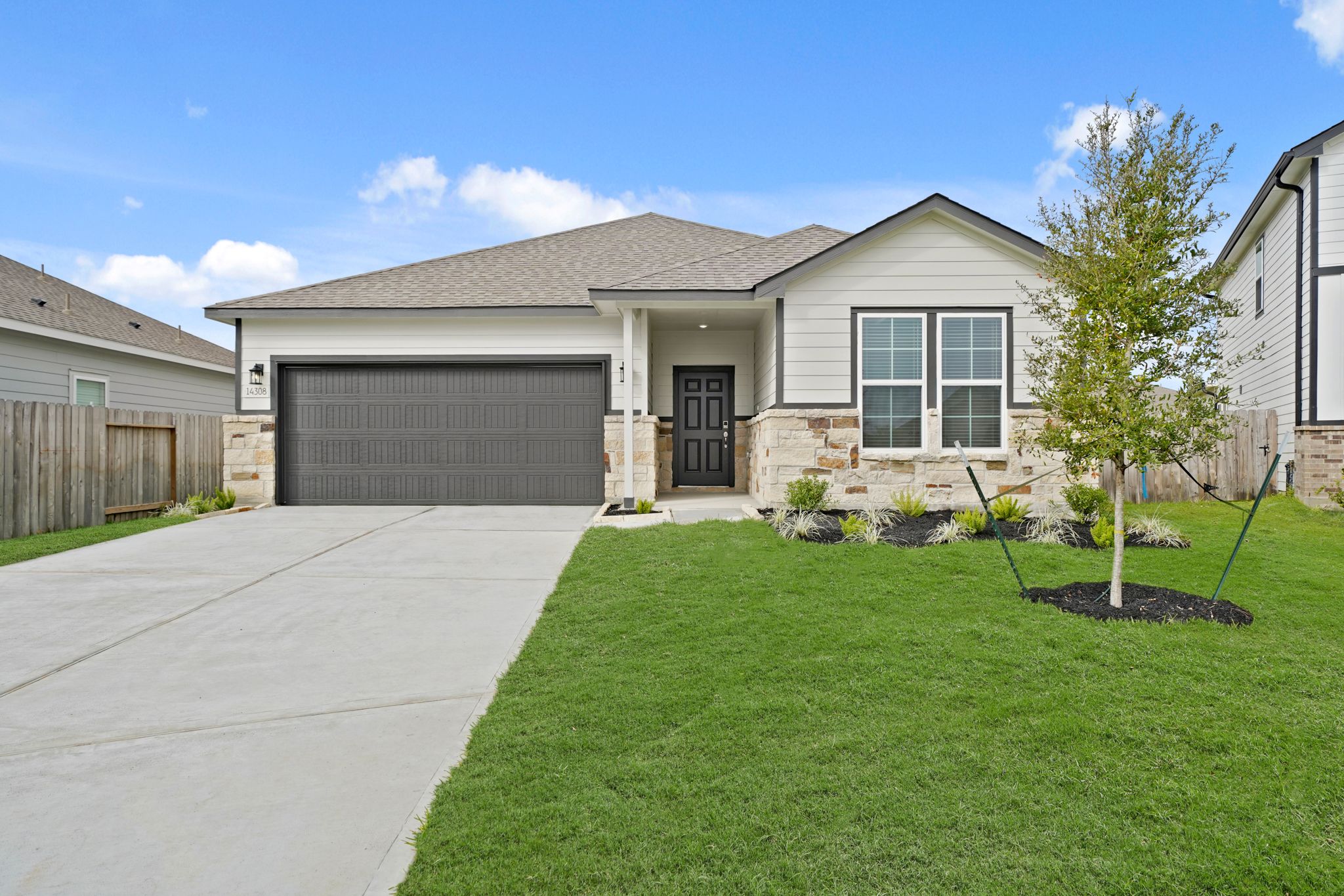 A house with a driveway and a tree in the front.
