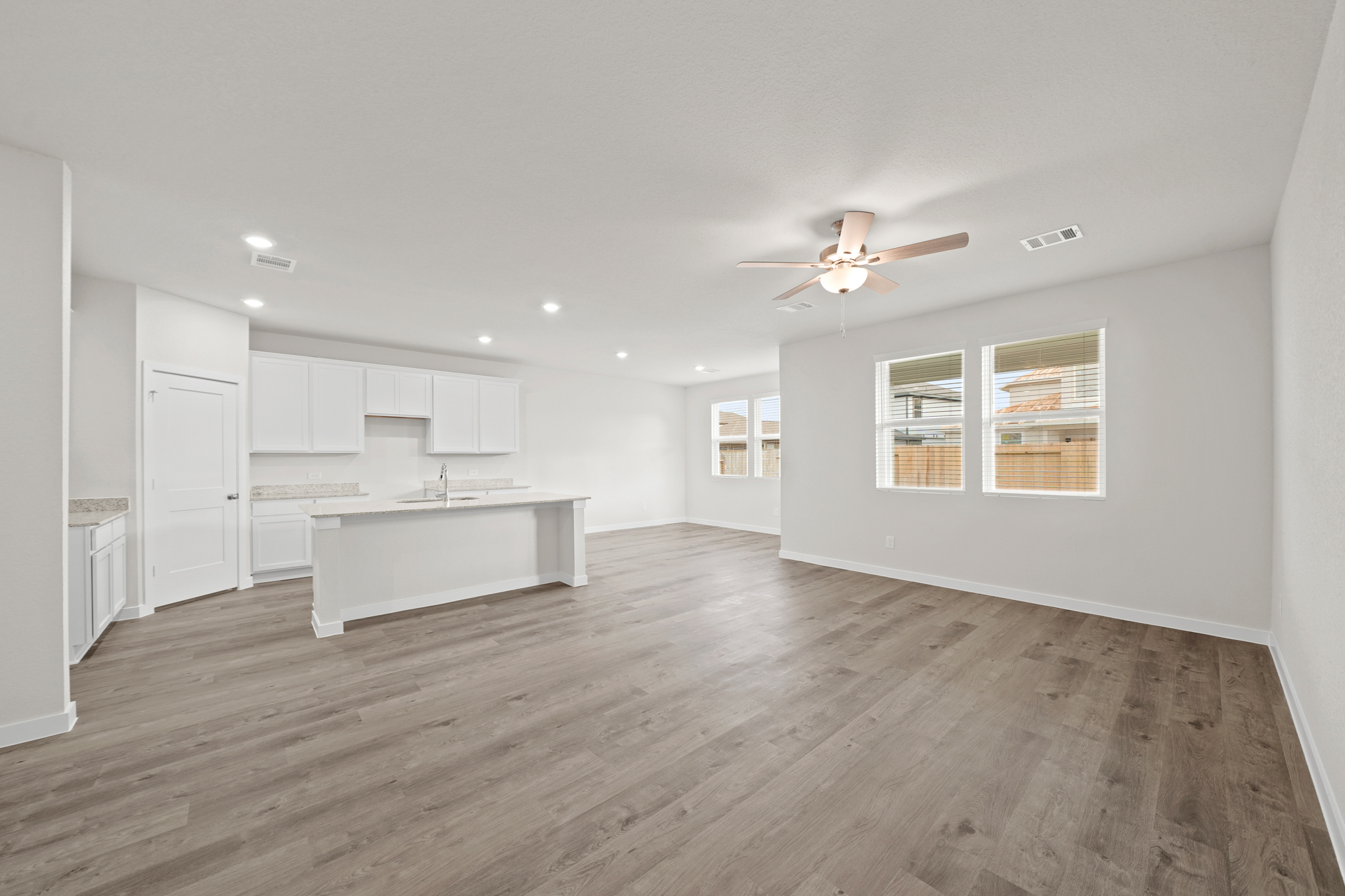 A large empty room with a wood floor and a ceiling fan.