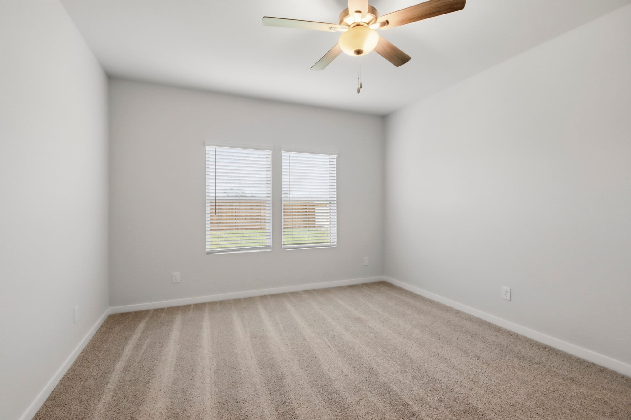 A room with a ceiling fan and a carpet.