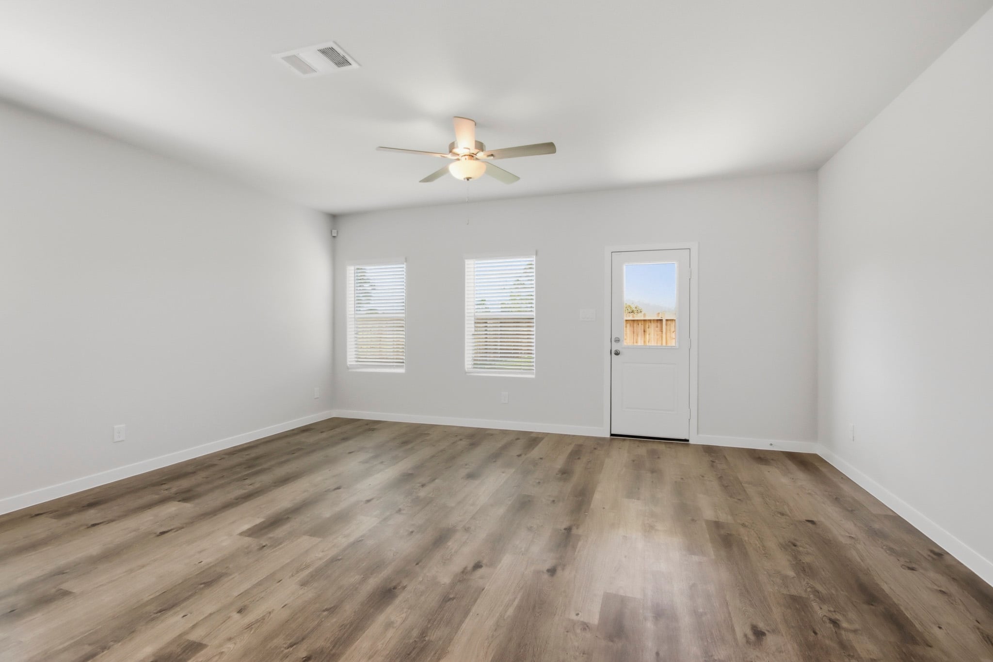 A room with a ceiling fan and a wood floor.