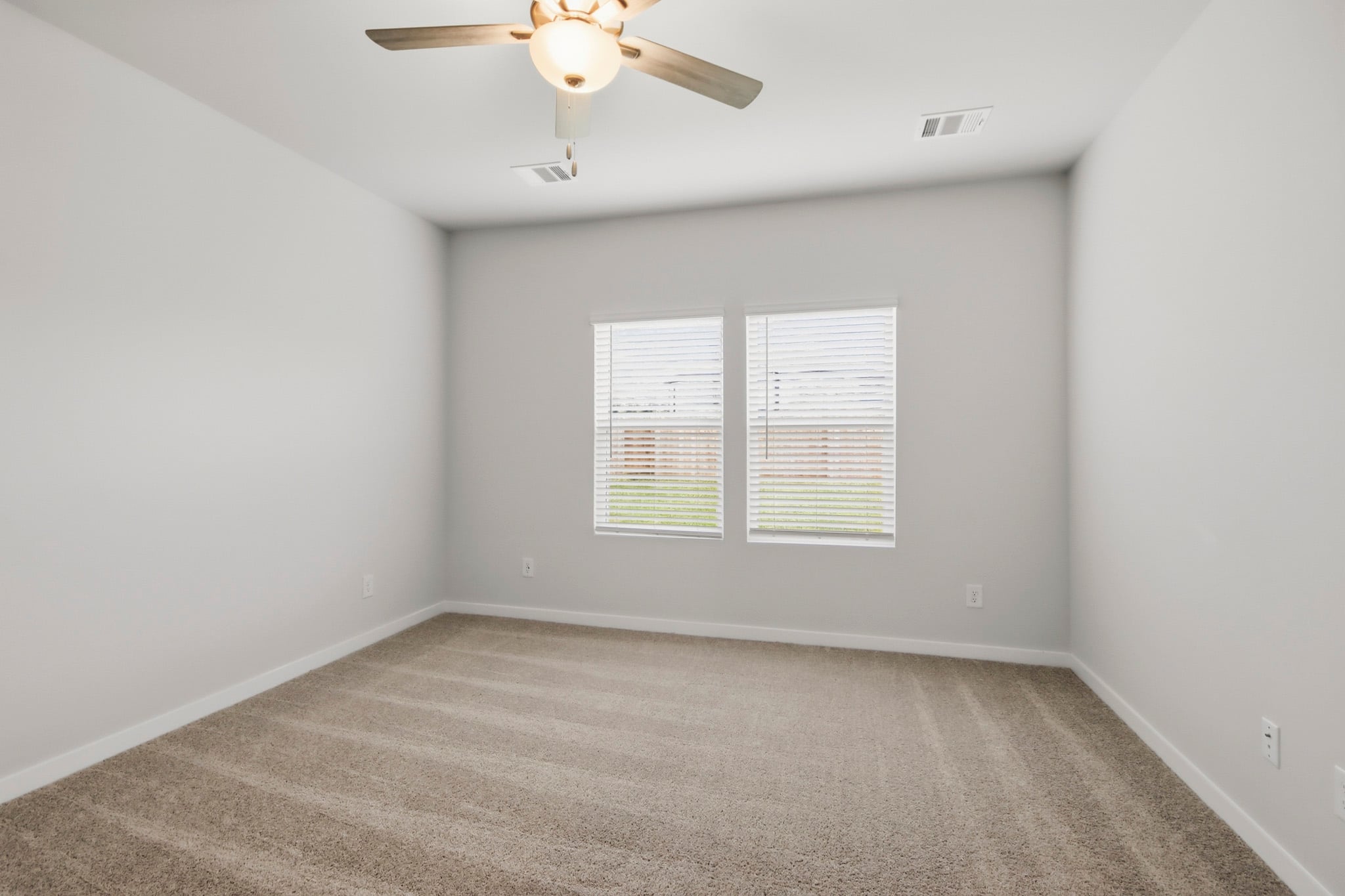A room with a ceiling fan and a carpet.