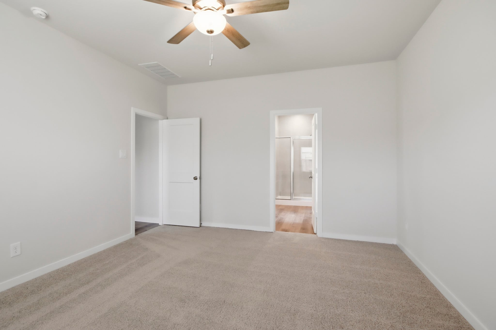 A room with a ceiling fan and a door.