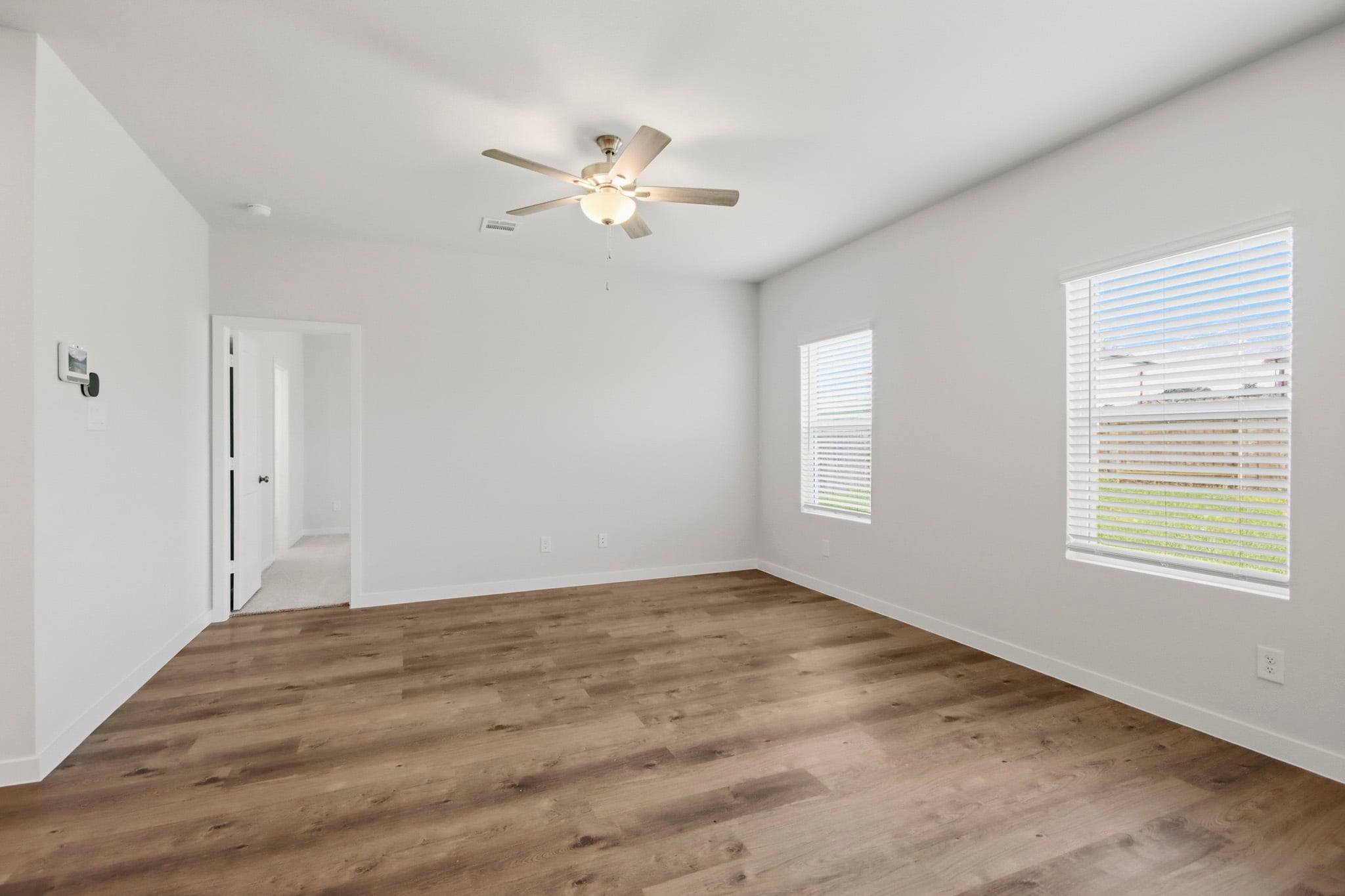 A room with a ceiling fan and wood floor.