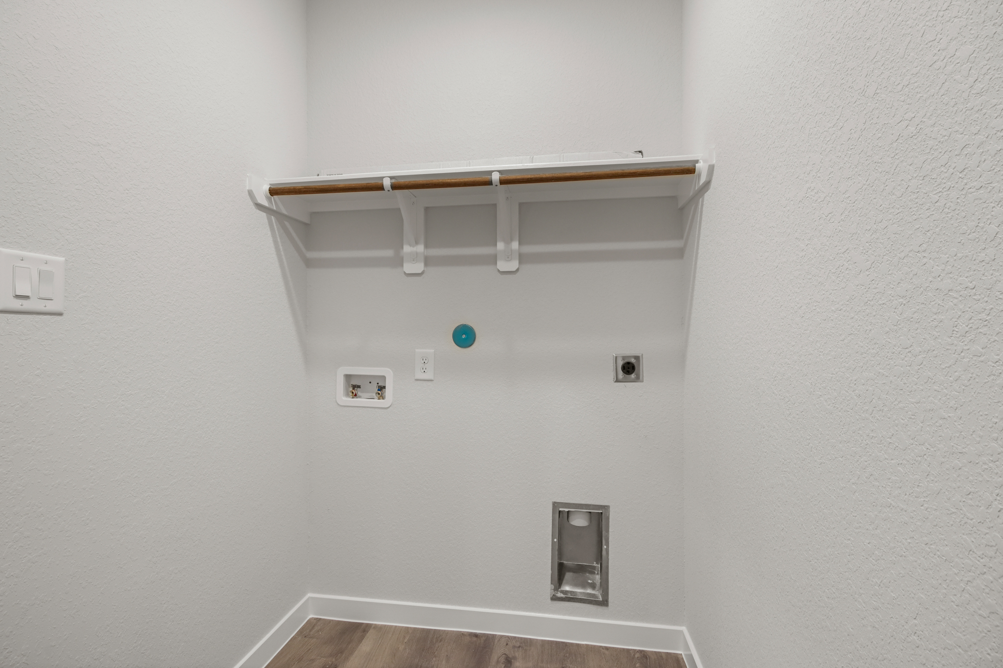 A white wall with a shelf and a light fixture.