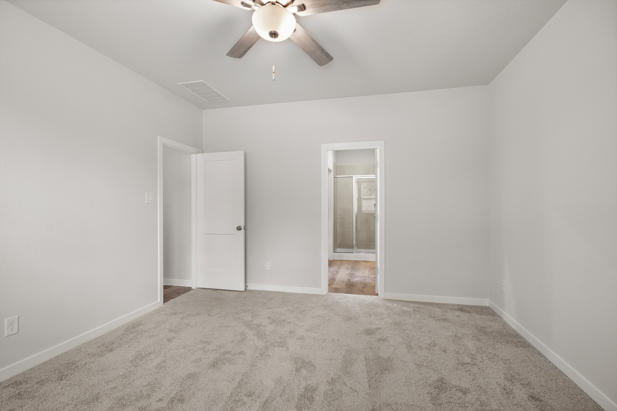 A room with a ceiling fan and a door.