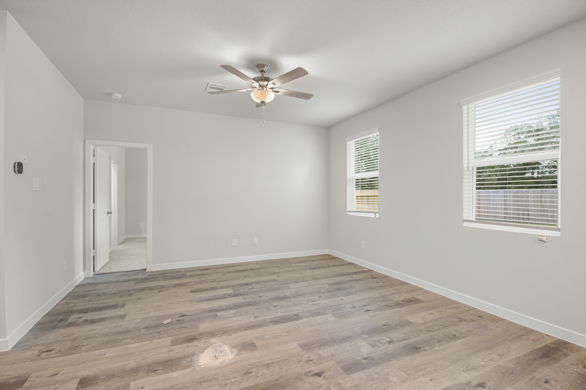 A room with a ceiling fan and a wood floor.